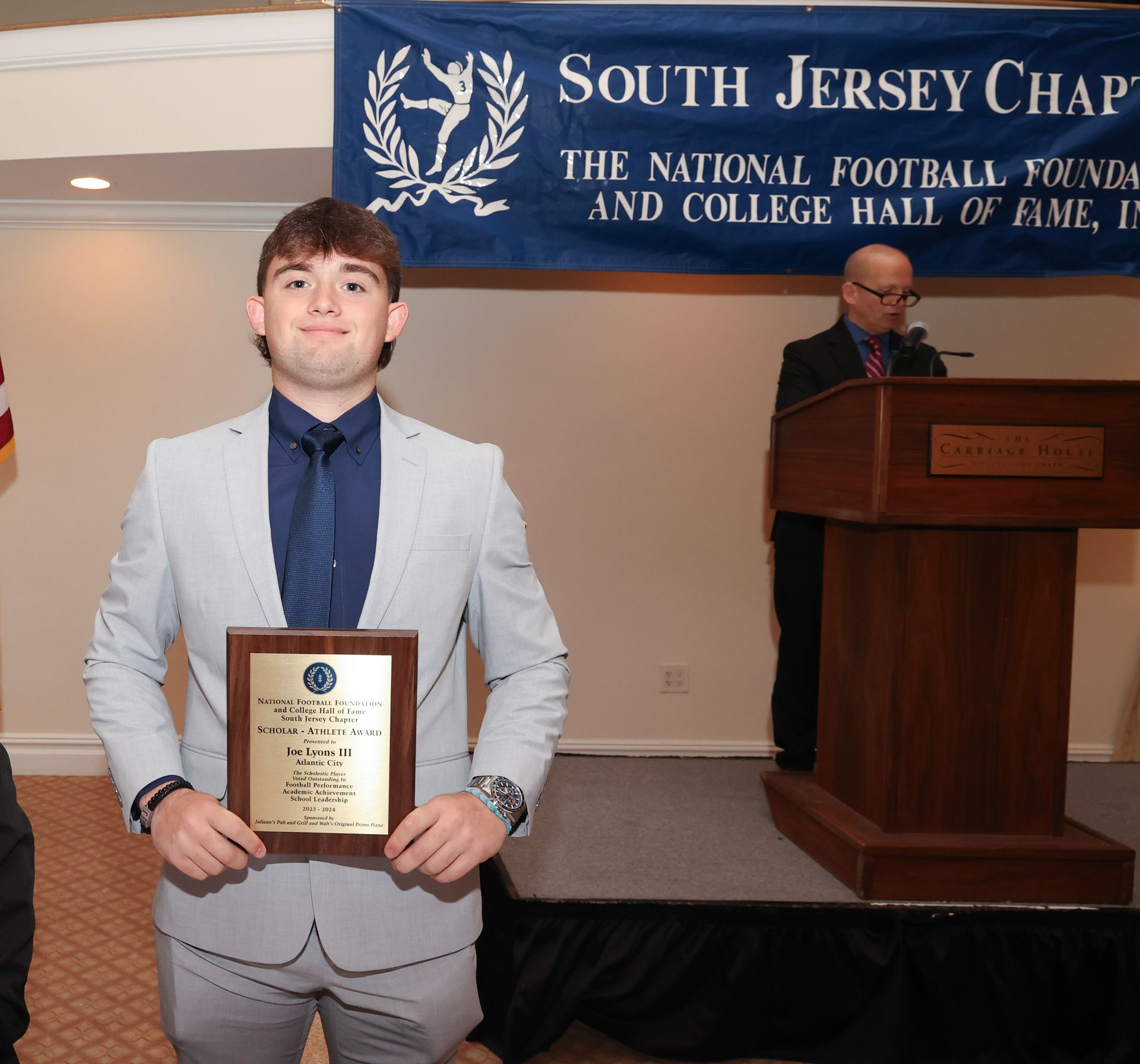 A man holding a plaque in front of a banner that says south jersey chapter