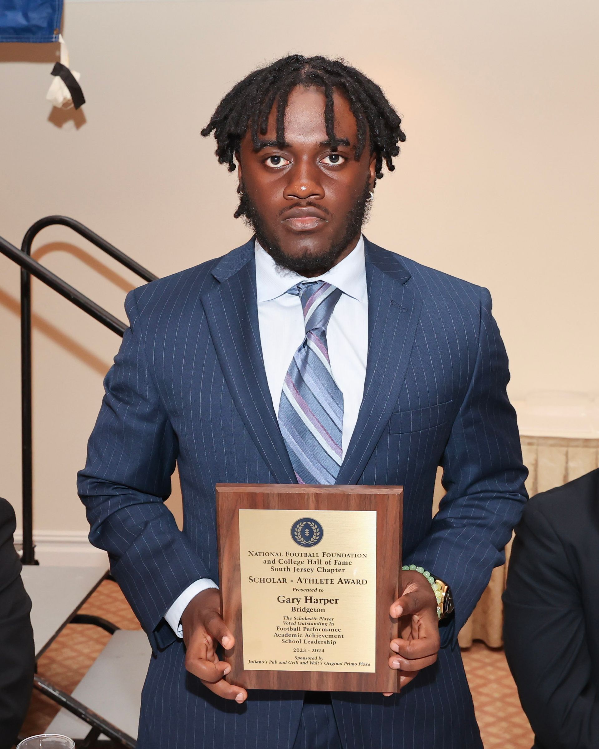 A man in a suit and tie is holding a plaque