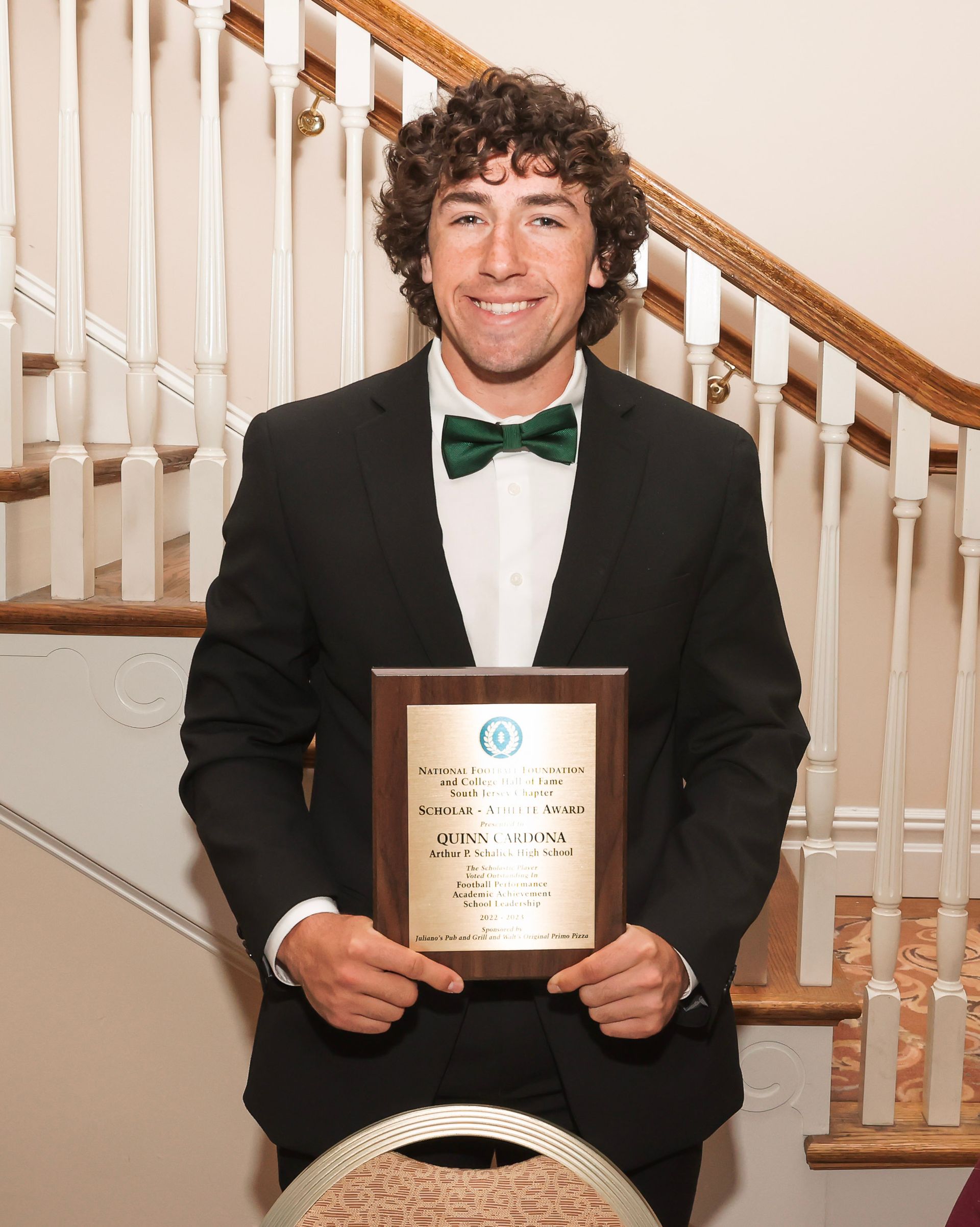 a man in a suit and bow tie is holding a plaque
