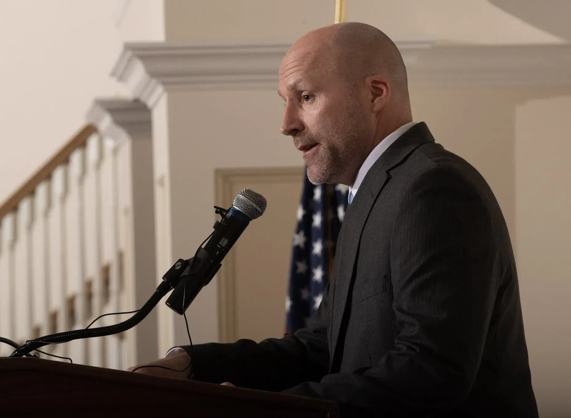 a man in a suit is standing at a podium speaking into a microphone .