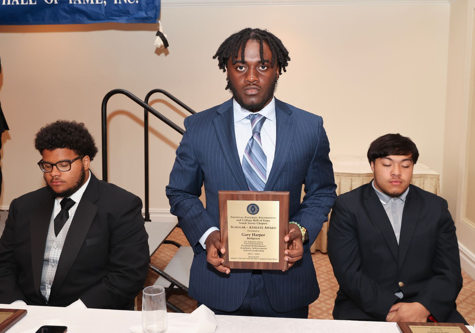 A man in a suit and tie is holding a plaque