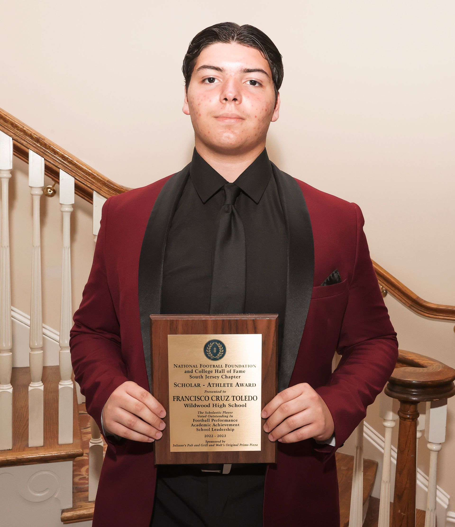 a man in a red jacket is holding a plaque that says 2014