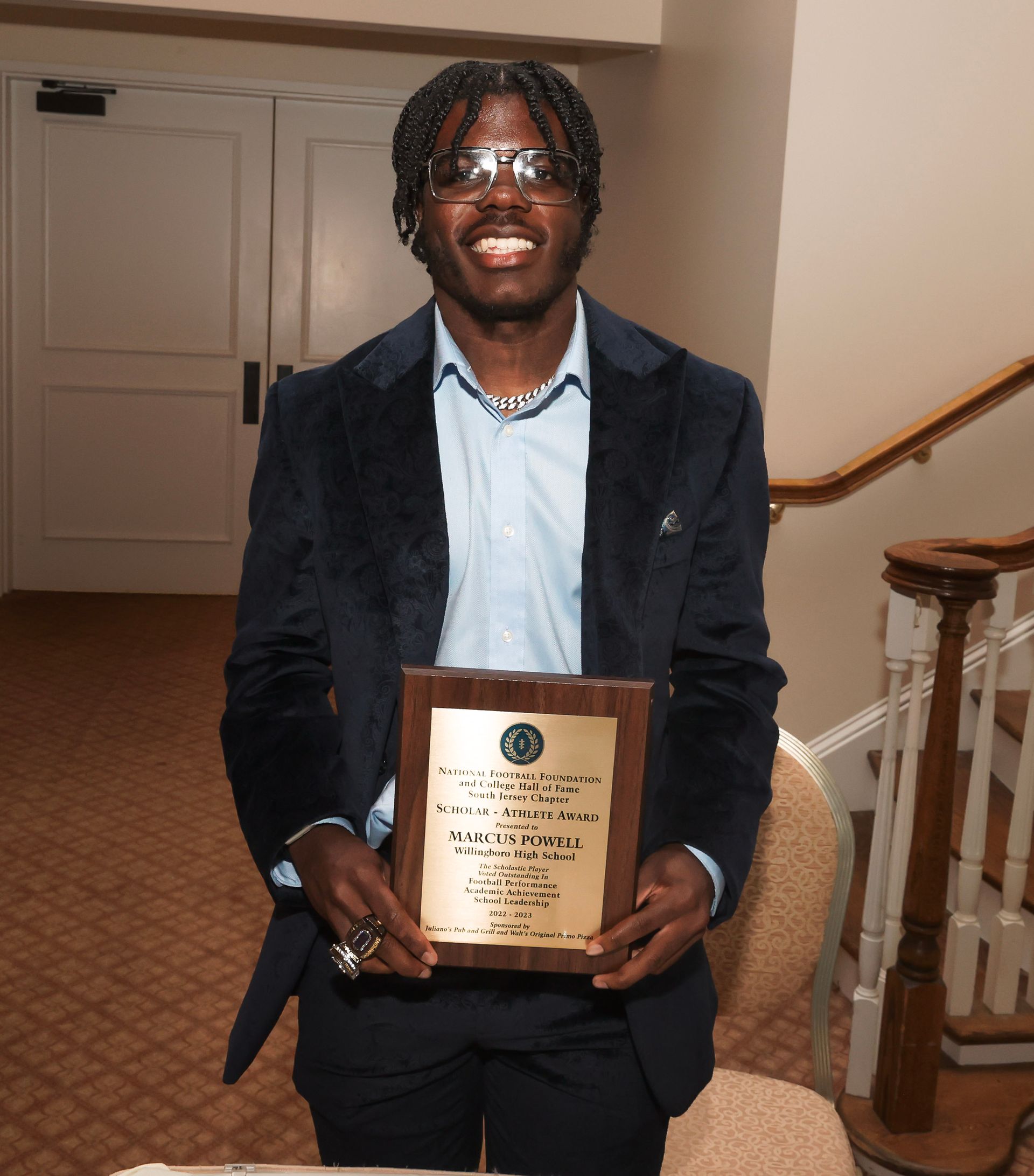 a man in a suit is holding a plaque that says ' a ' on it