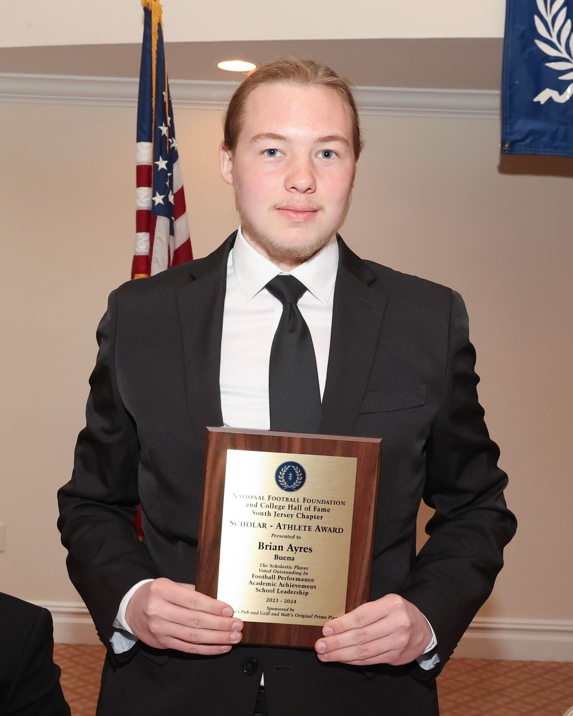 A man in a suit and tie is holding a plaque