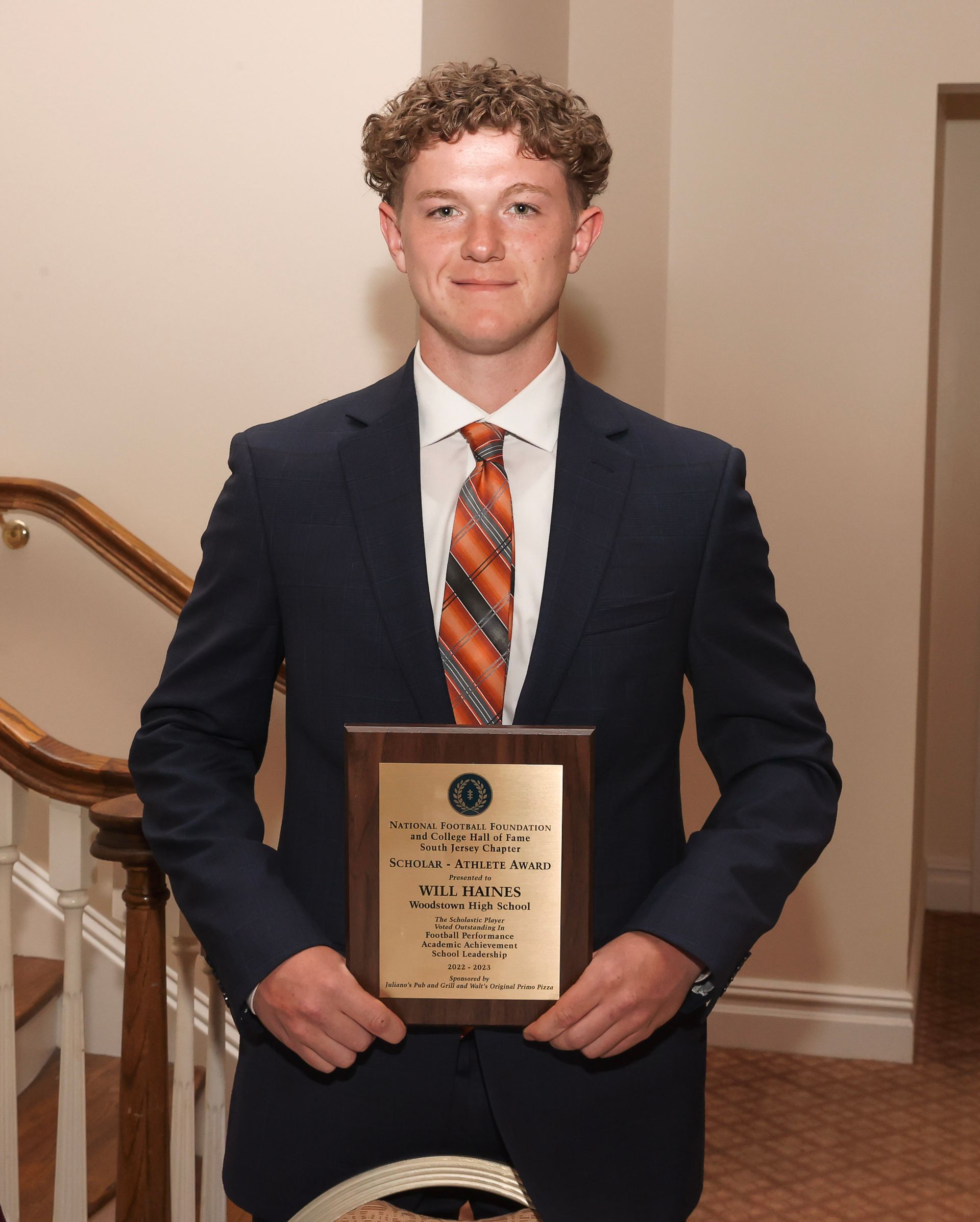 a young man in a suit and tie is holding a plaque