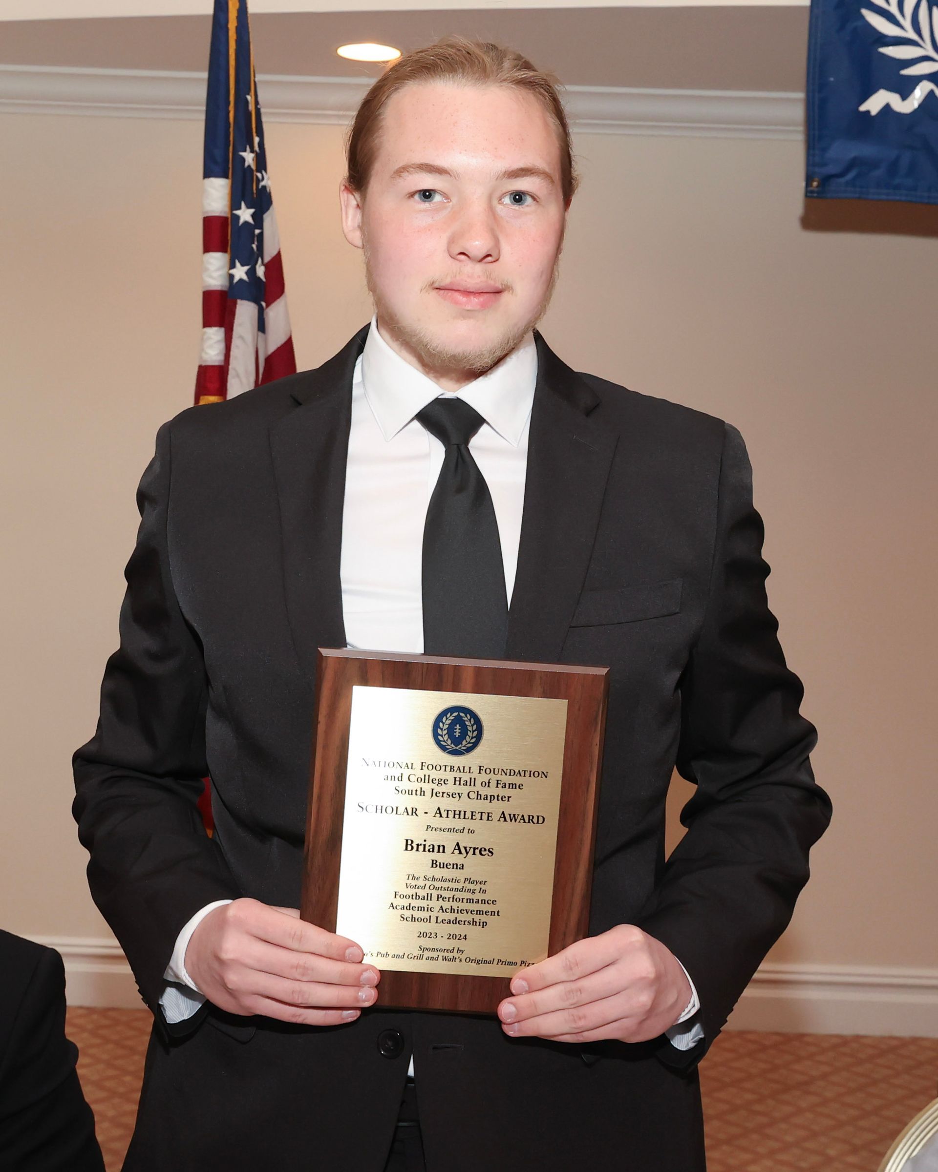 A man in a suit and tie is holding a plaque