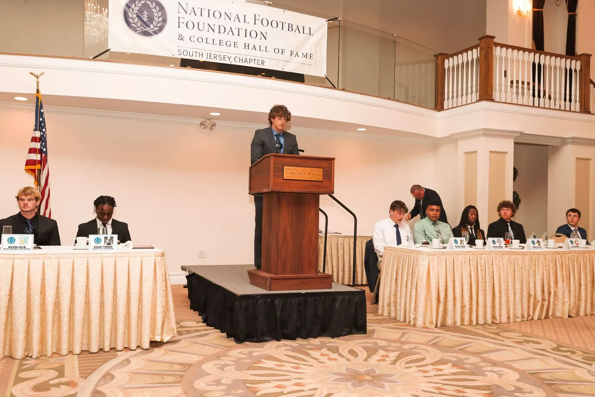 a man stands at a podium giving a speech in front of a group of people