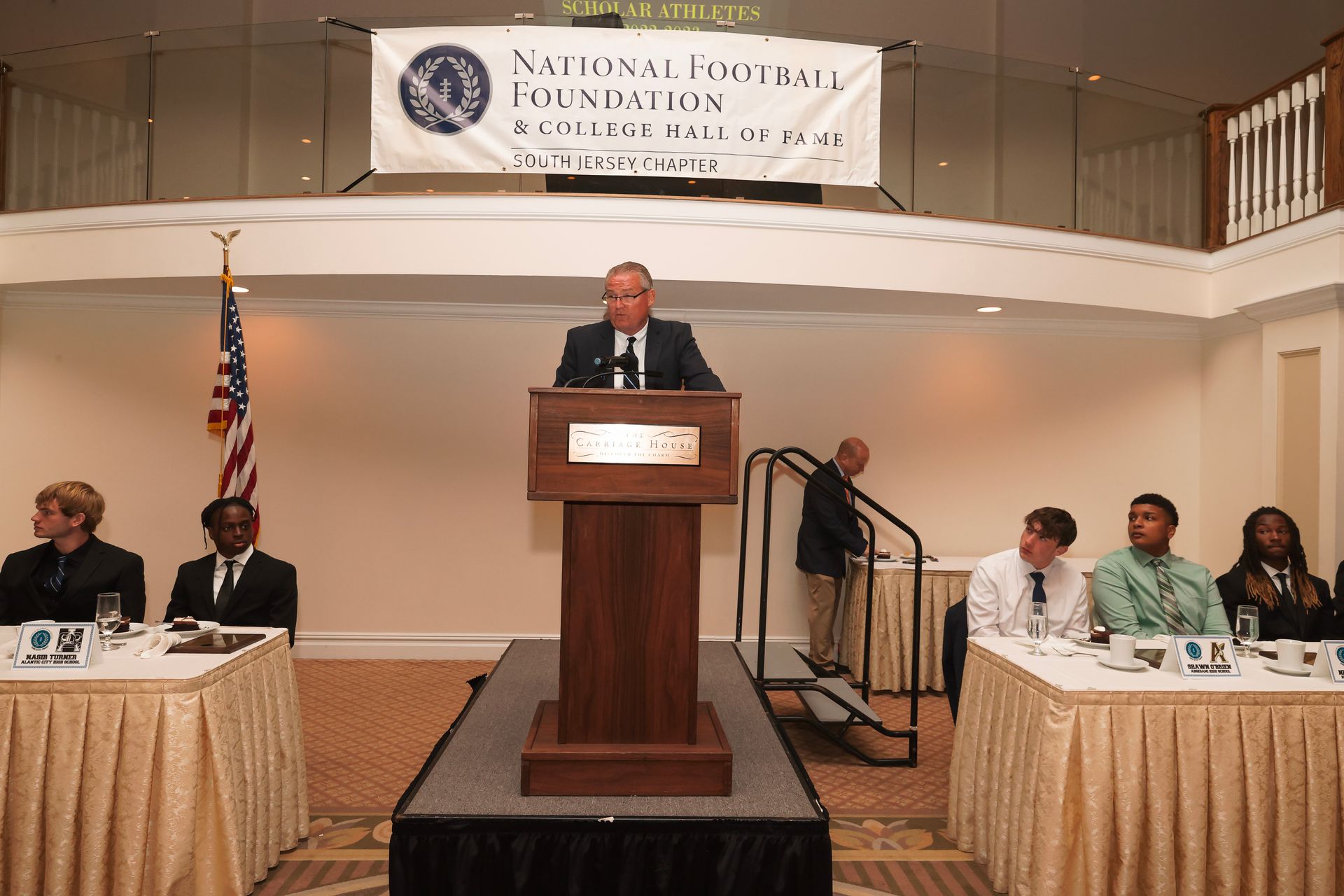 a man stands at a podium in front of a national theatre sign