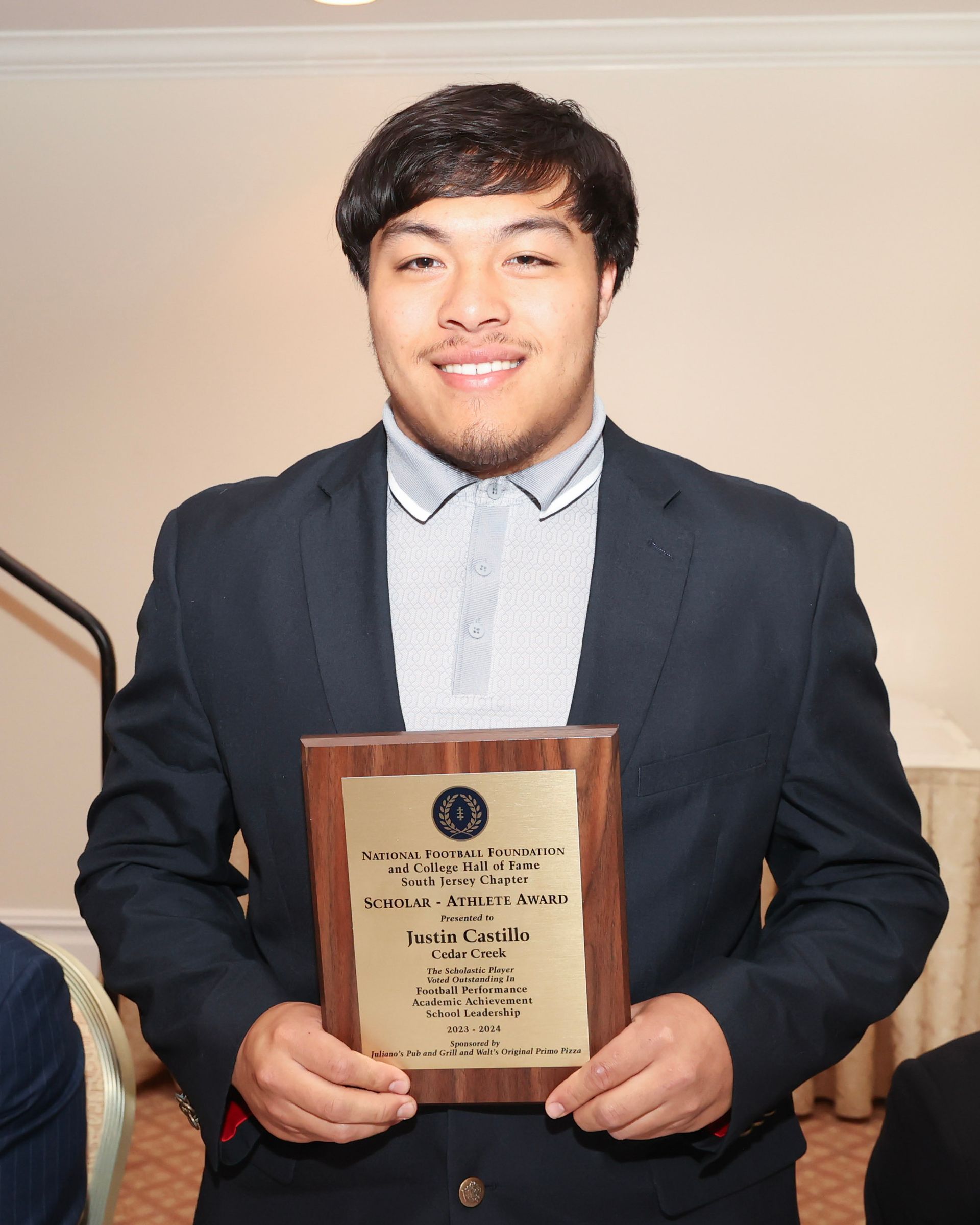 A man in a suit is holding a plaque that says ' jc ' on it