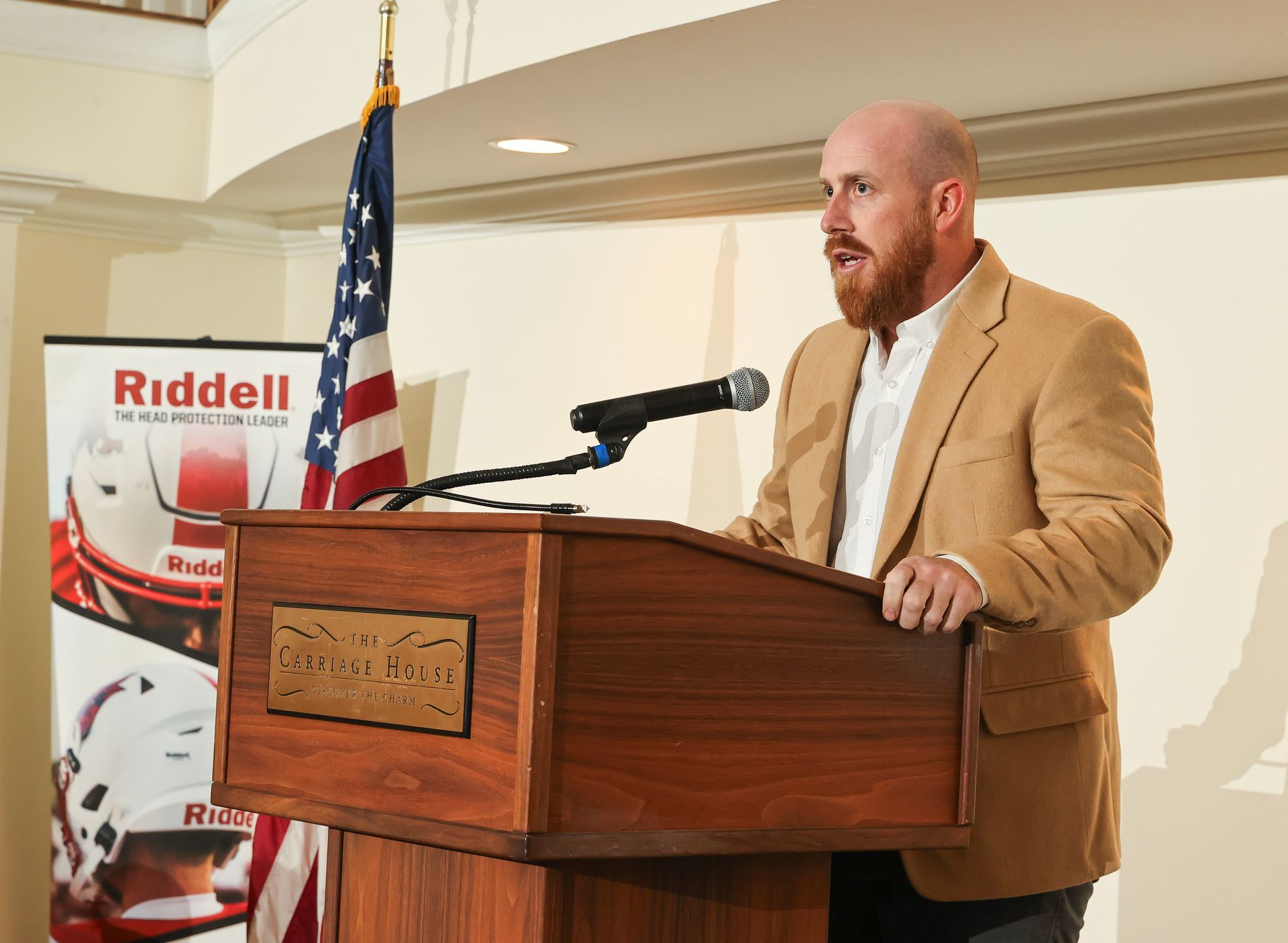 A man is standing at a podium with a microphone in front of an american flag