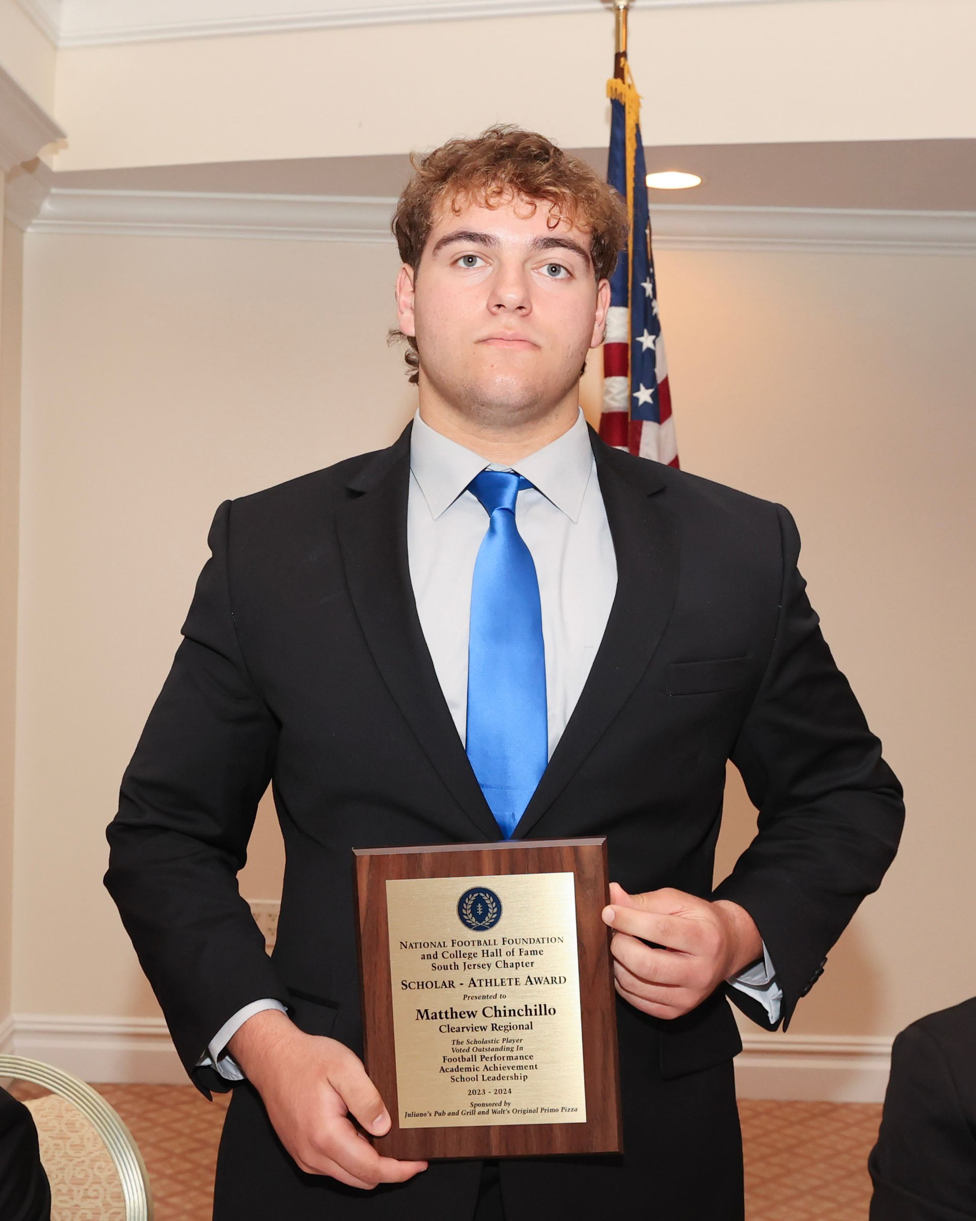A man in a suit and tie is holding a plaque