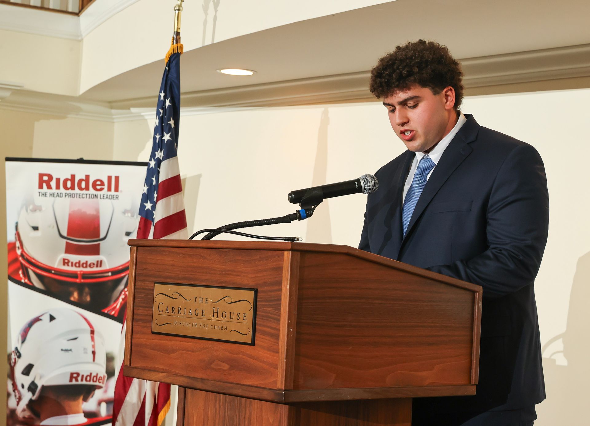 John Scibilia standing in front of a podium giving a speech