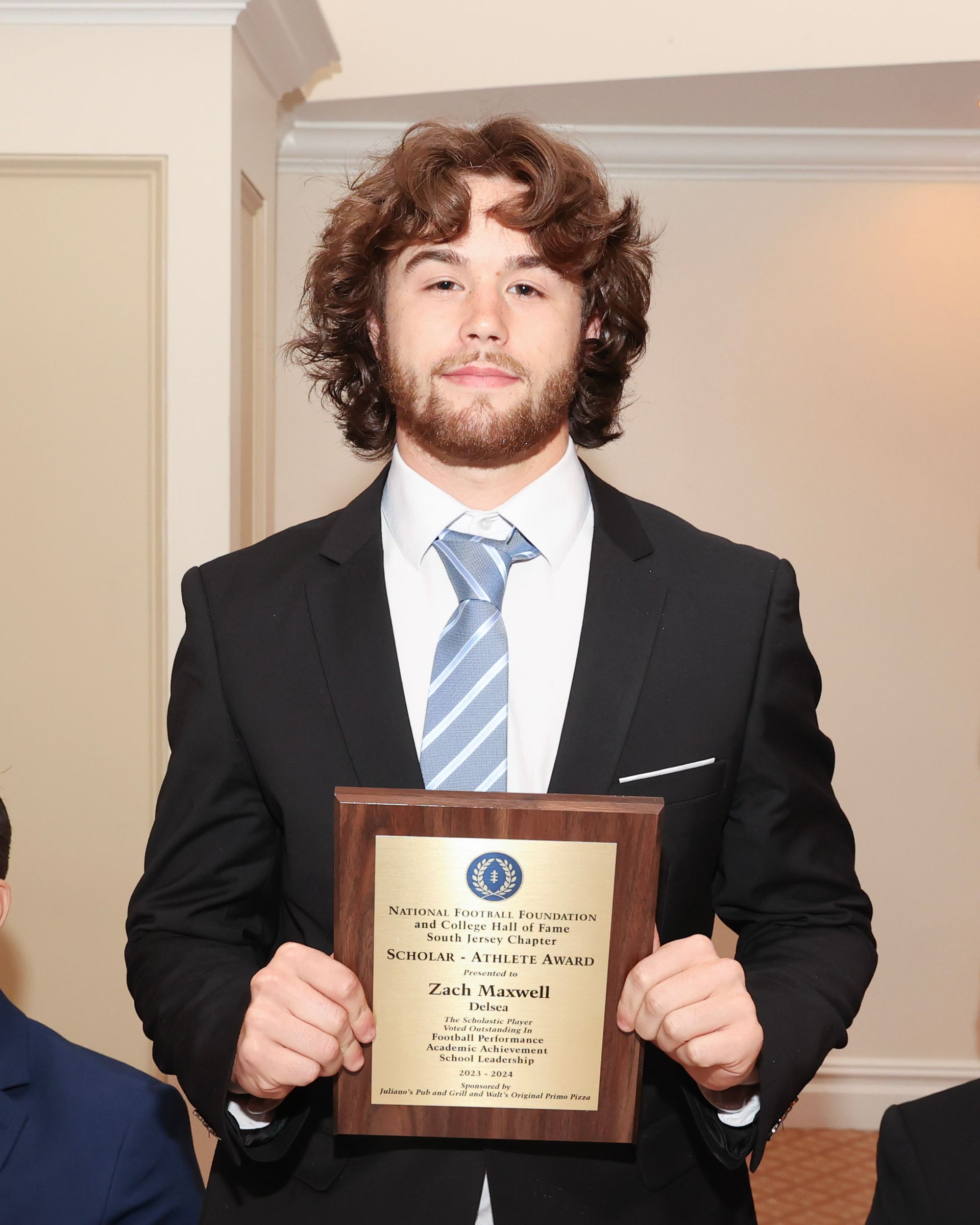A man in a suit and tie is holding a plaque