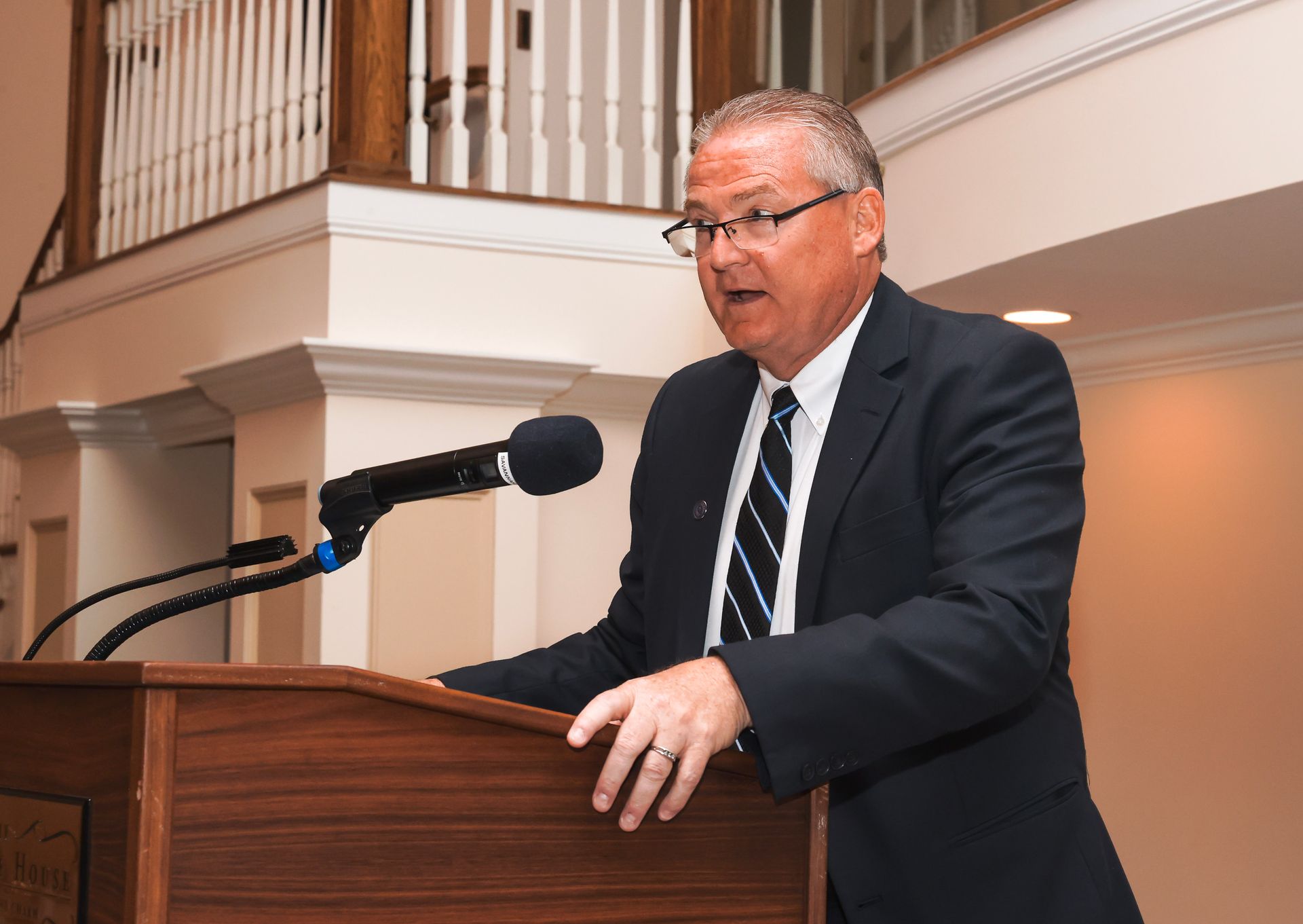 a man in a suit and tie is giving a speech at a podium