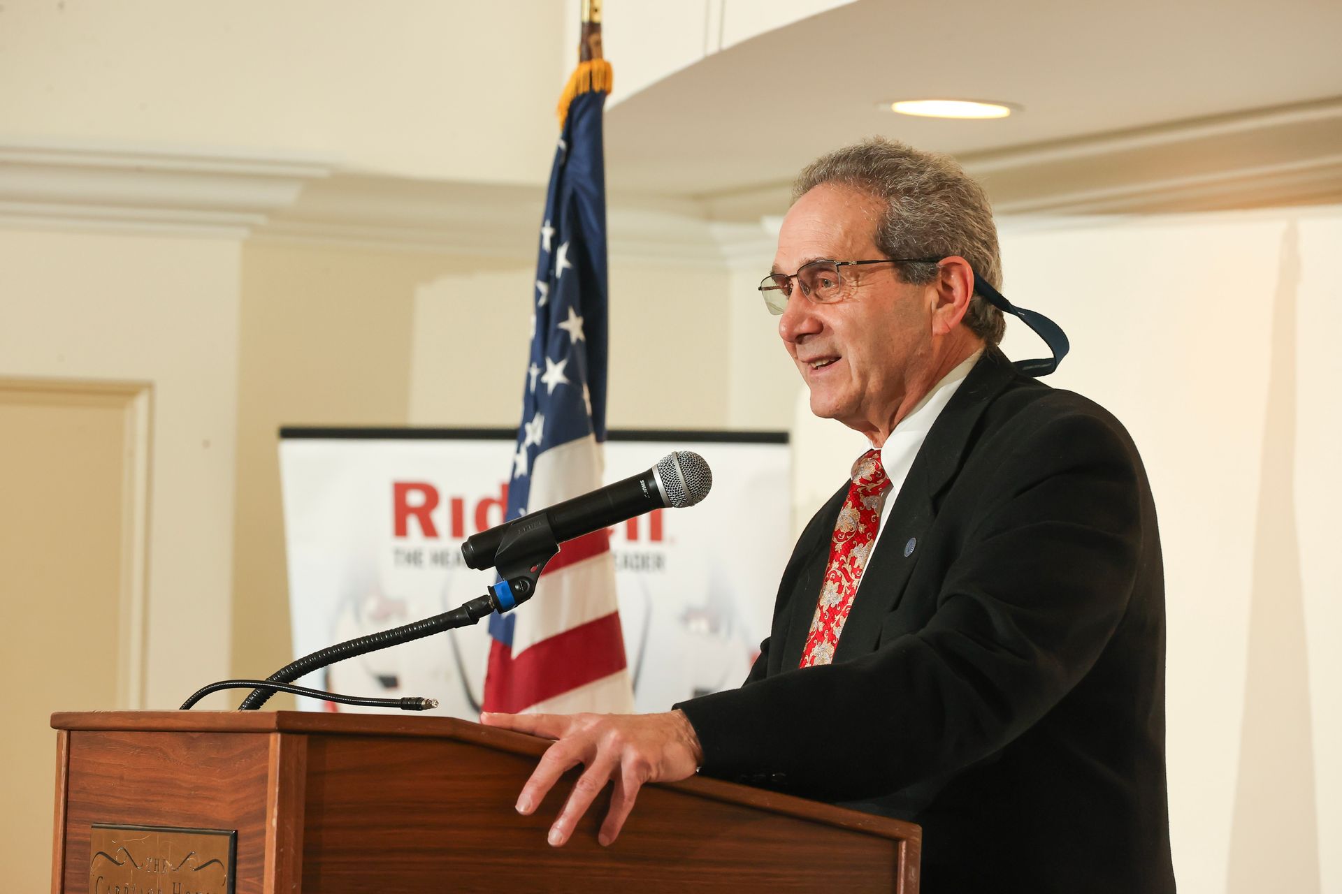 Ted D'Alessio standing in front of a podium giving a speech