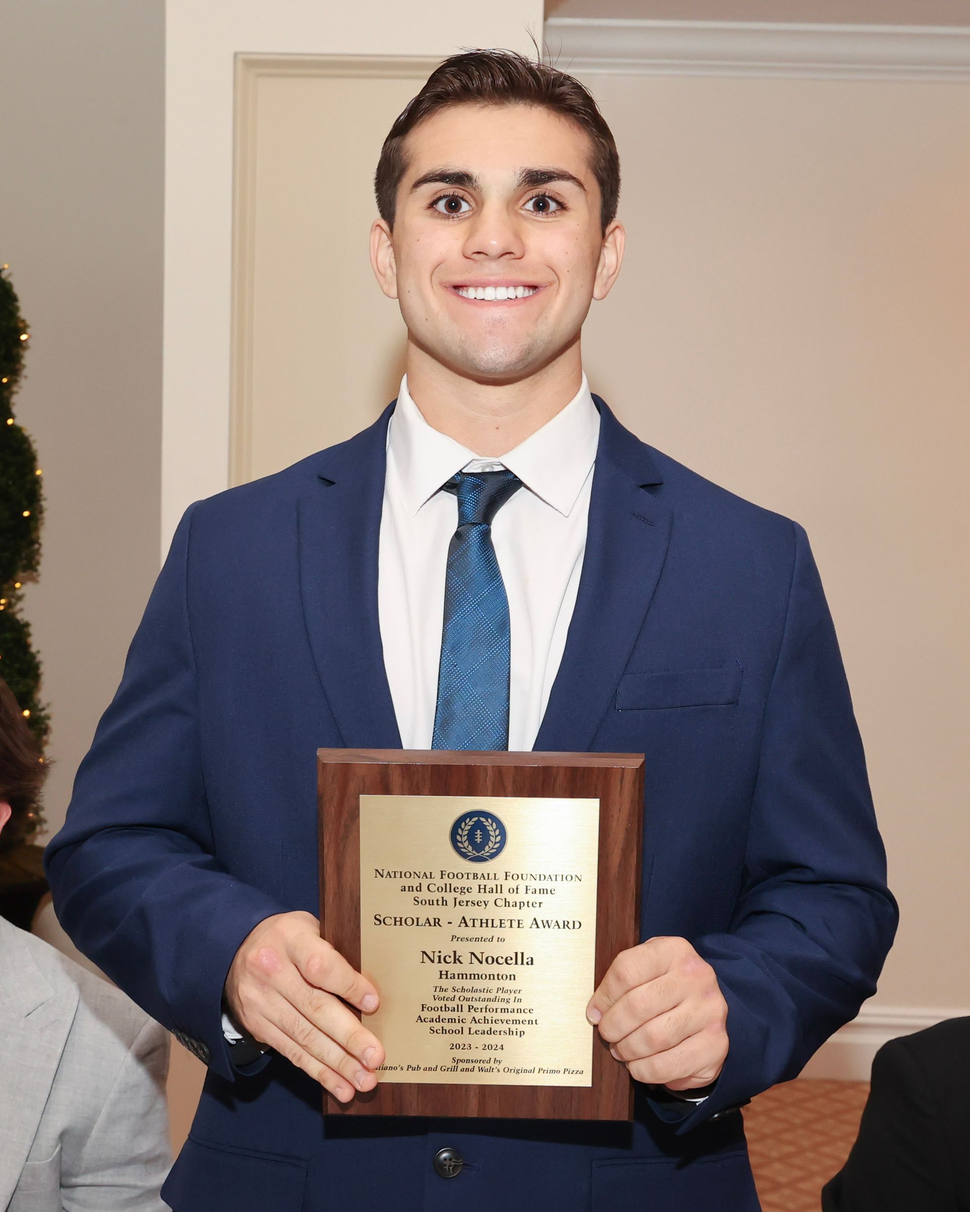 A man in a suit and tie is holding a plaque