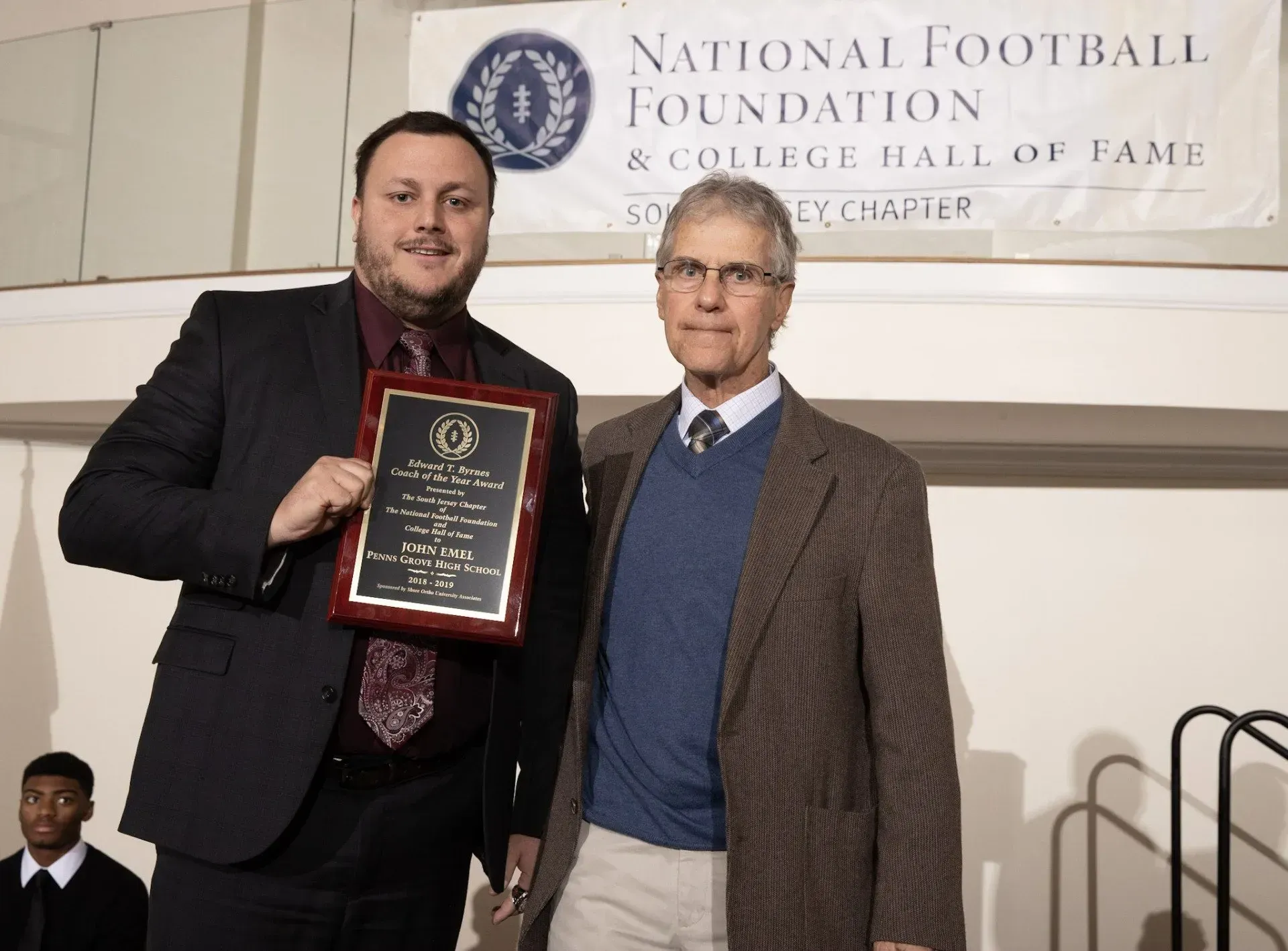 two men standing in front of a national football foundation banner