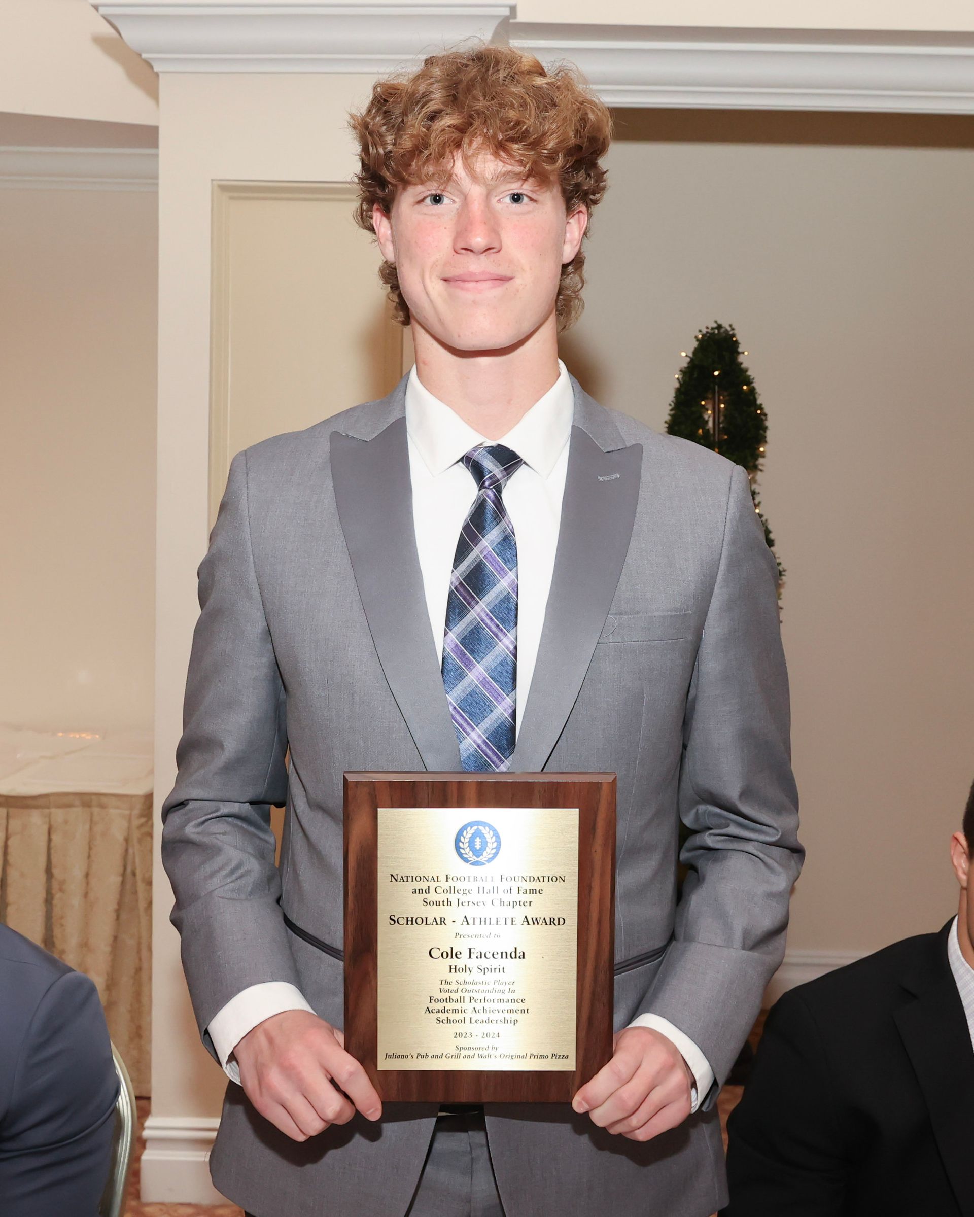 A man in a suit and tie is holding a plaque