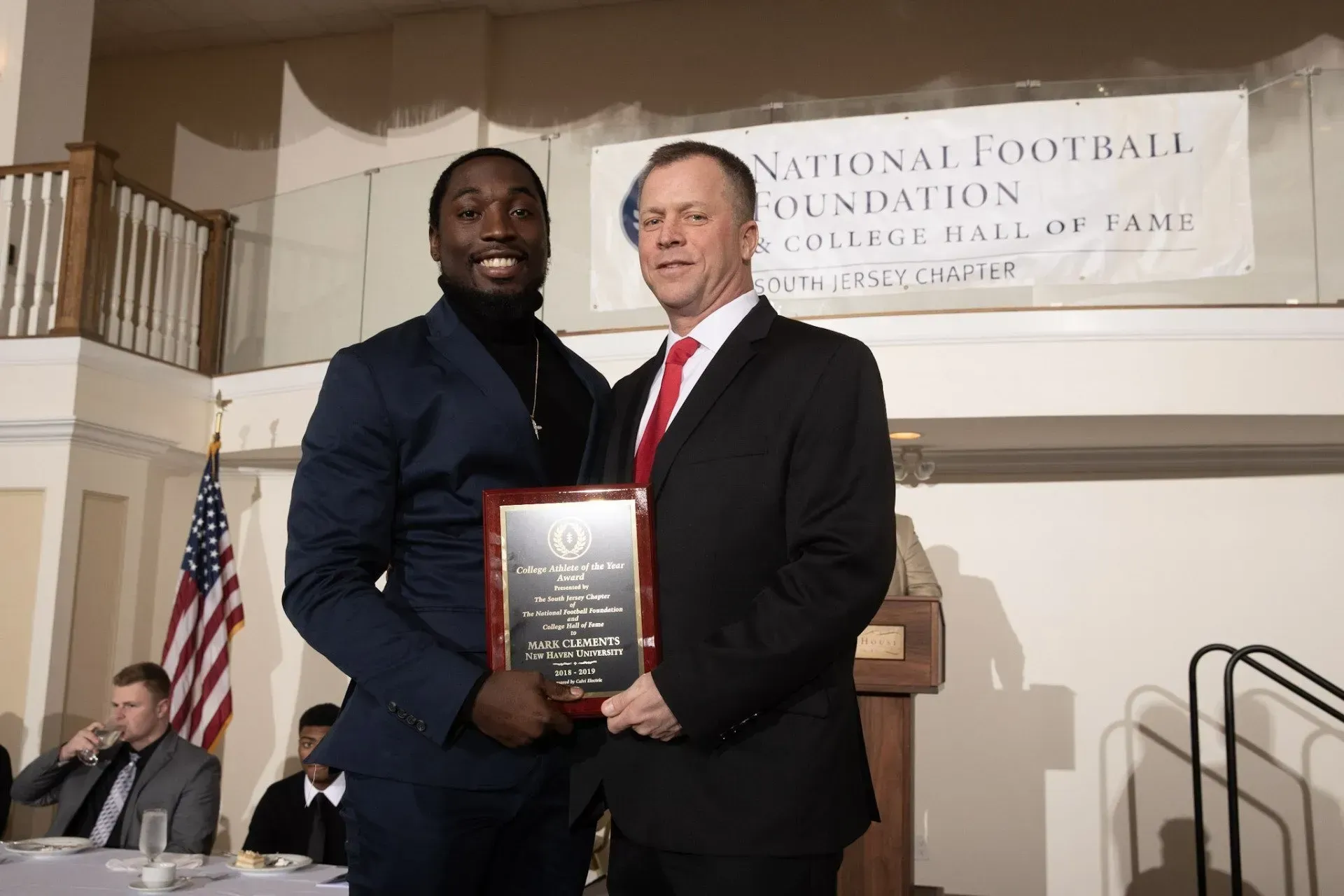 two men standing in front of a sign that says national football foundation