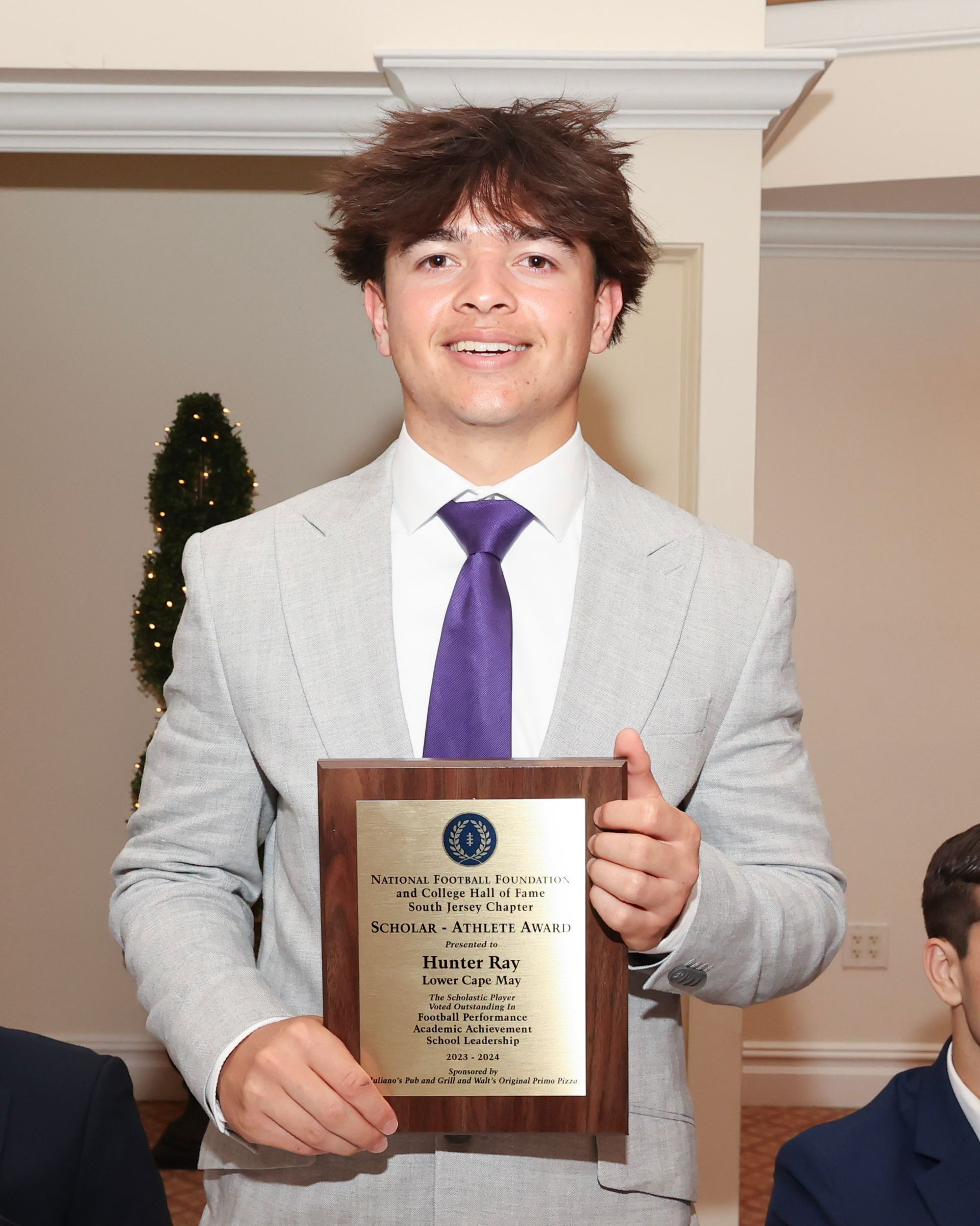 A young man in a suit and tie is holding a plaque