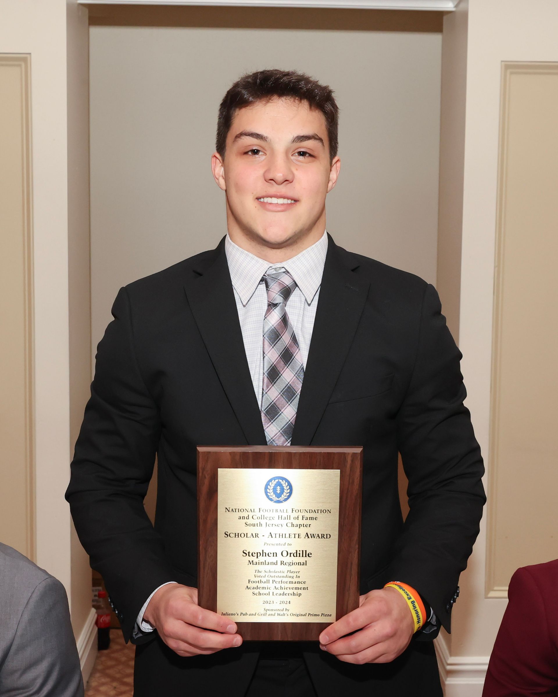 A man in a suit and tie is holding a plaque