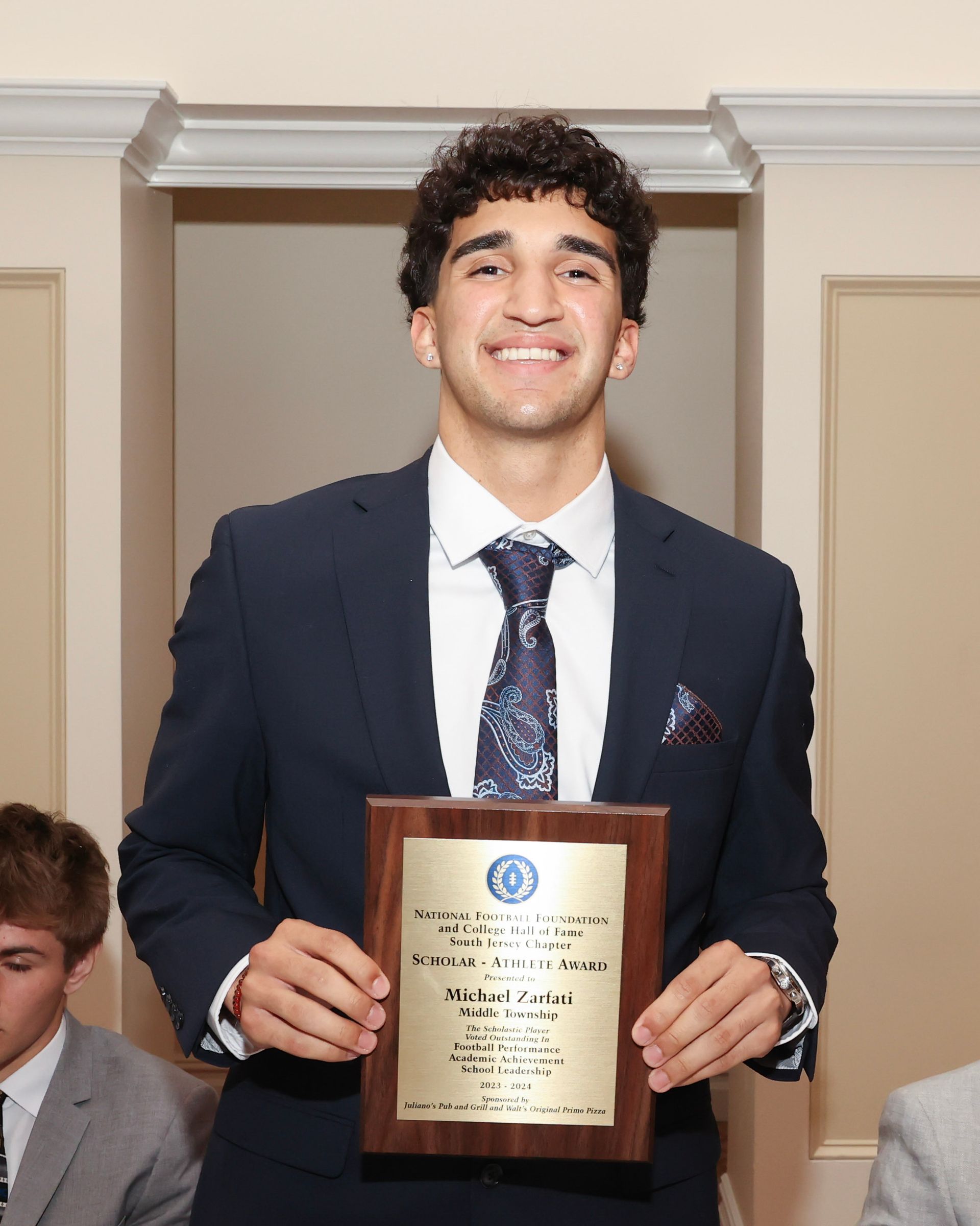 A man in a suit and tie is holding a plaque