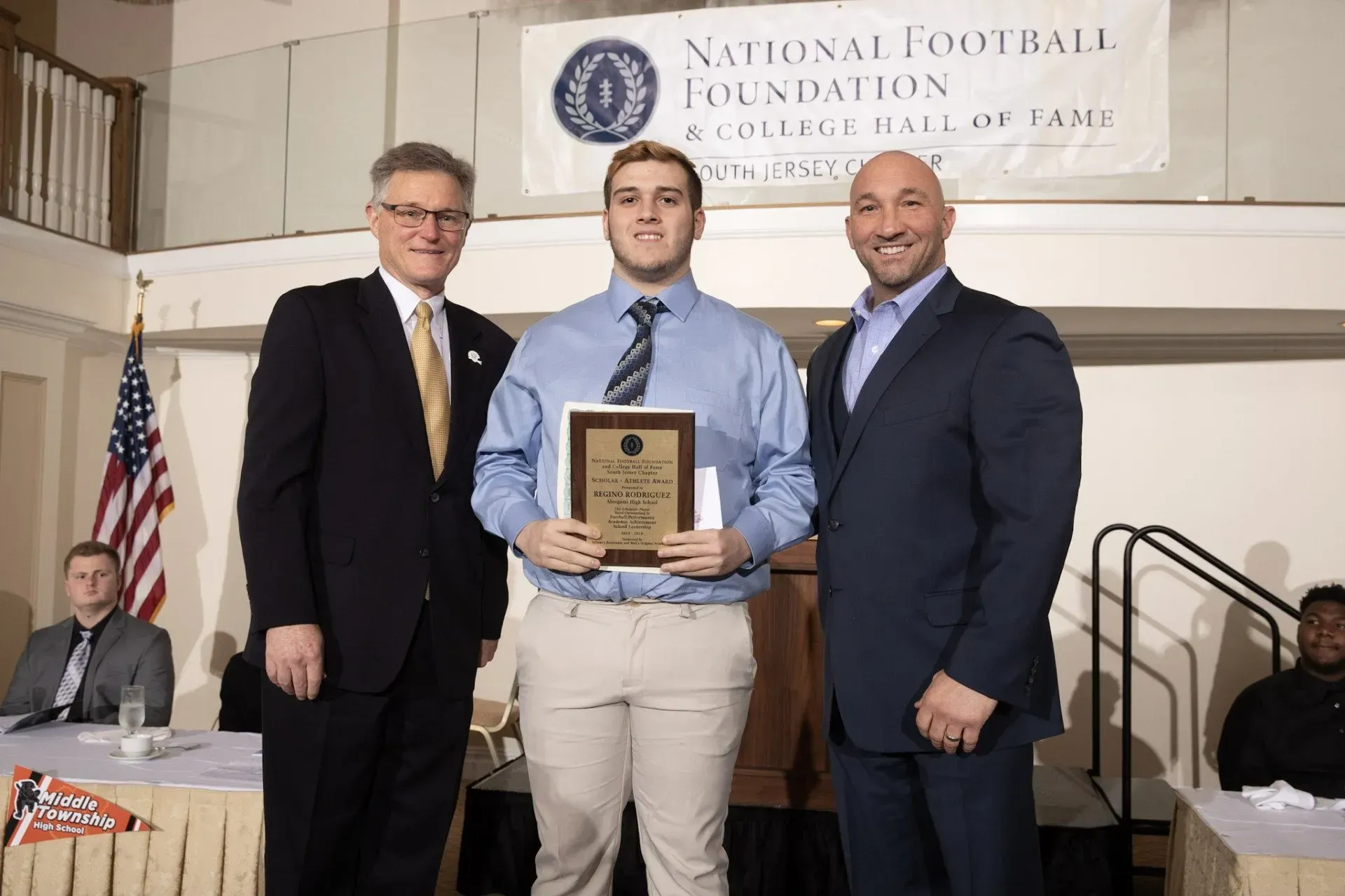 a man is holding a plaque in front of a national football foundation banner