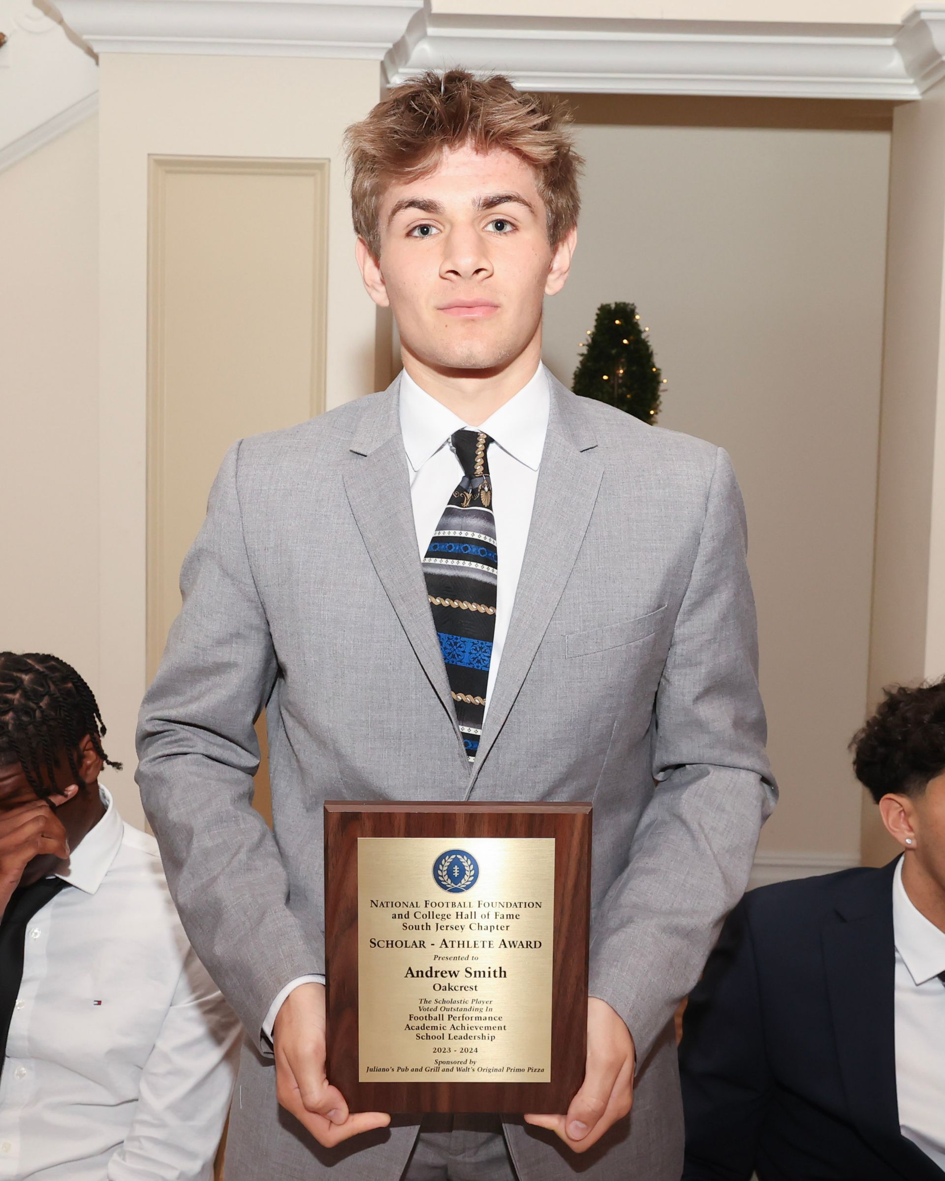 A man in a suit and tie is holding a plaque