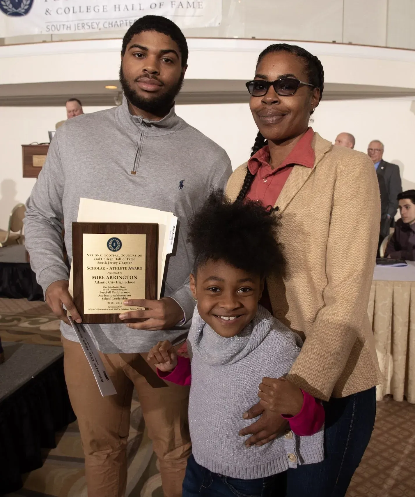 a man and woman holding a plaque and a little girl