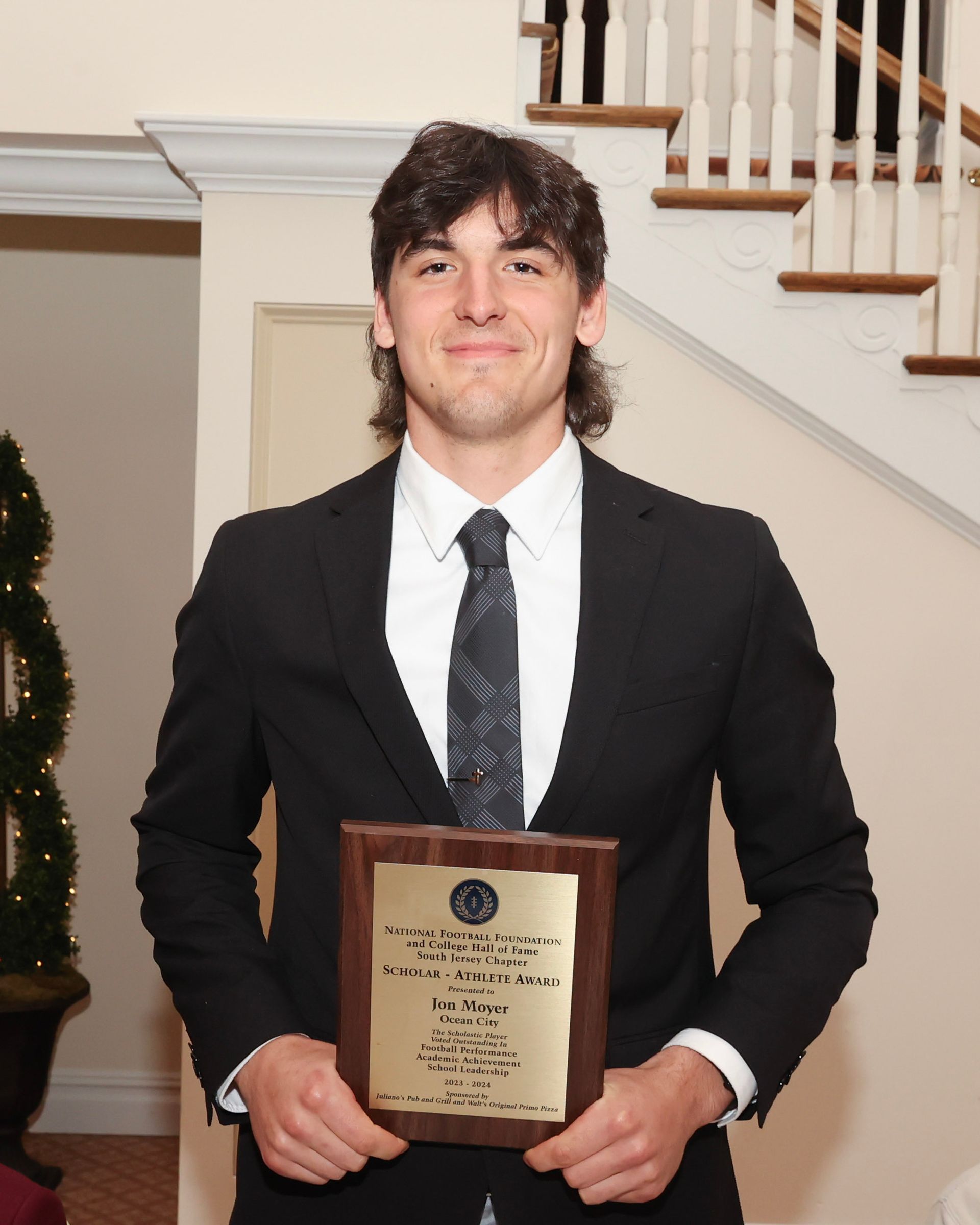 A man in a suit and tie is holding a plaque