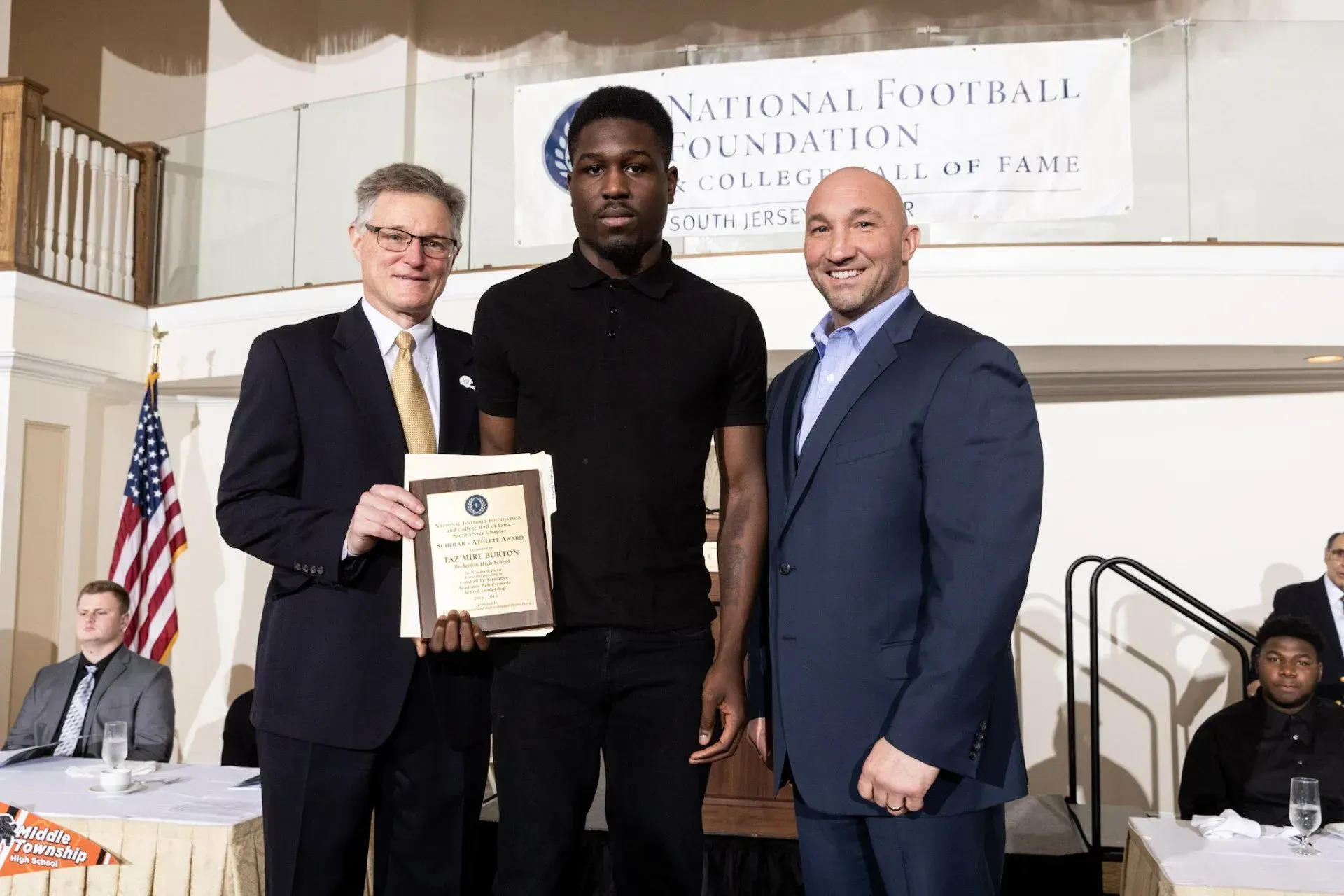 three men standing in front of a sign that says national football foundation