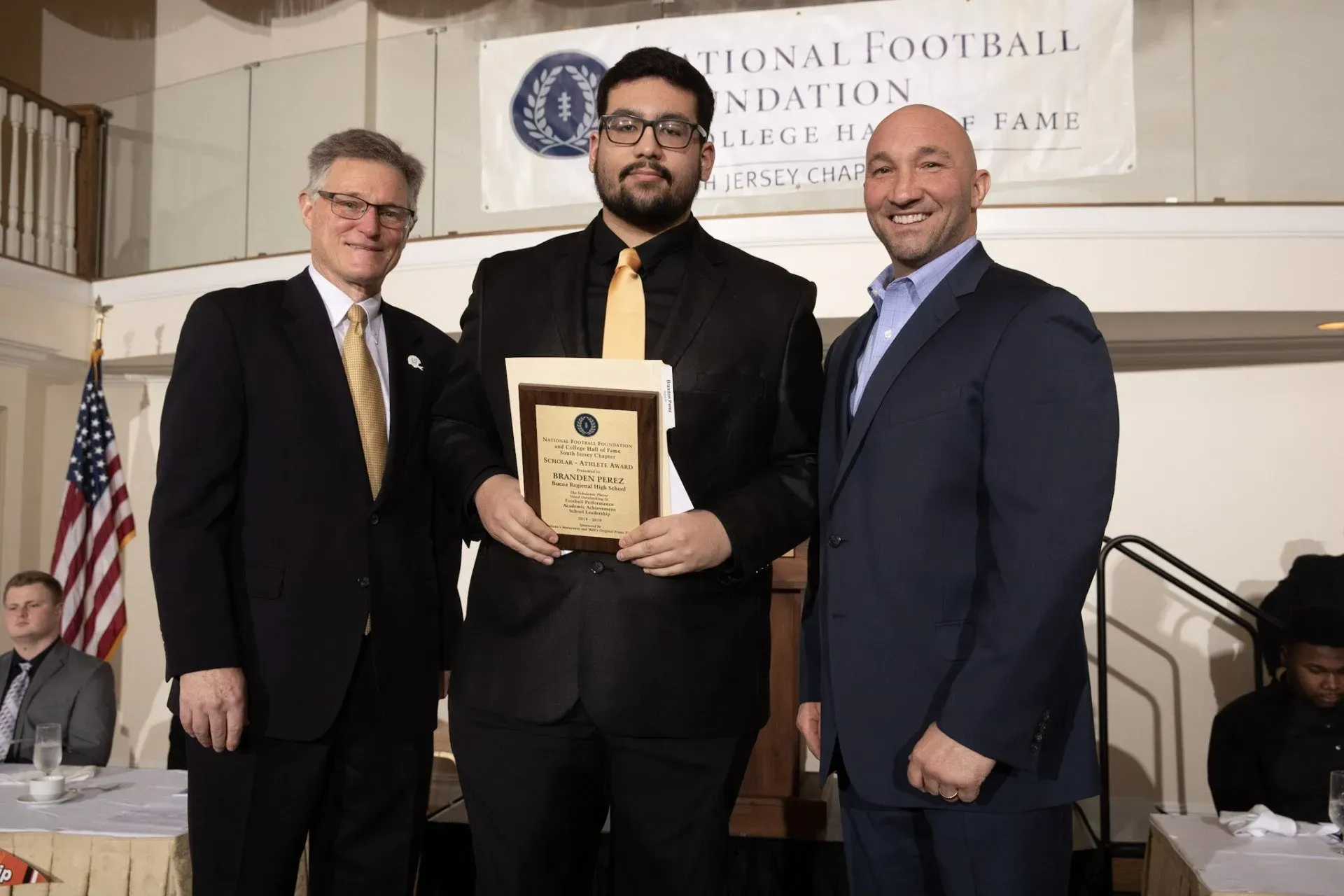 three men standing in front of a national football foundation banner