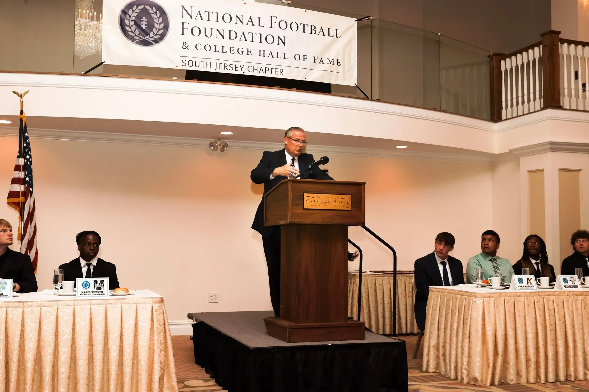 a man stands at a podium giving a speech in front of a sign that says national capital foundation
