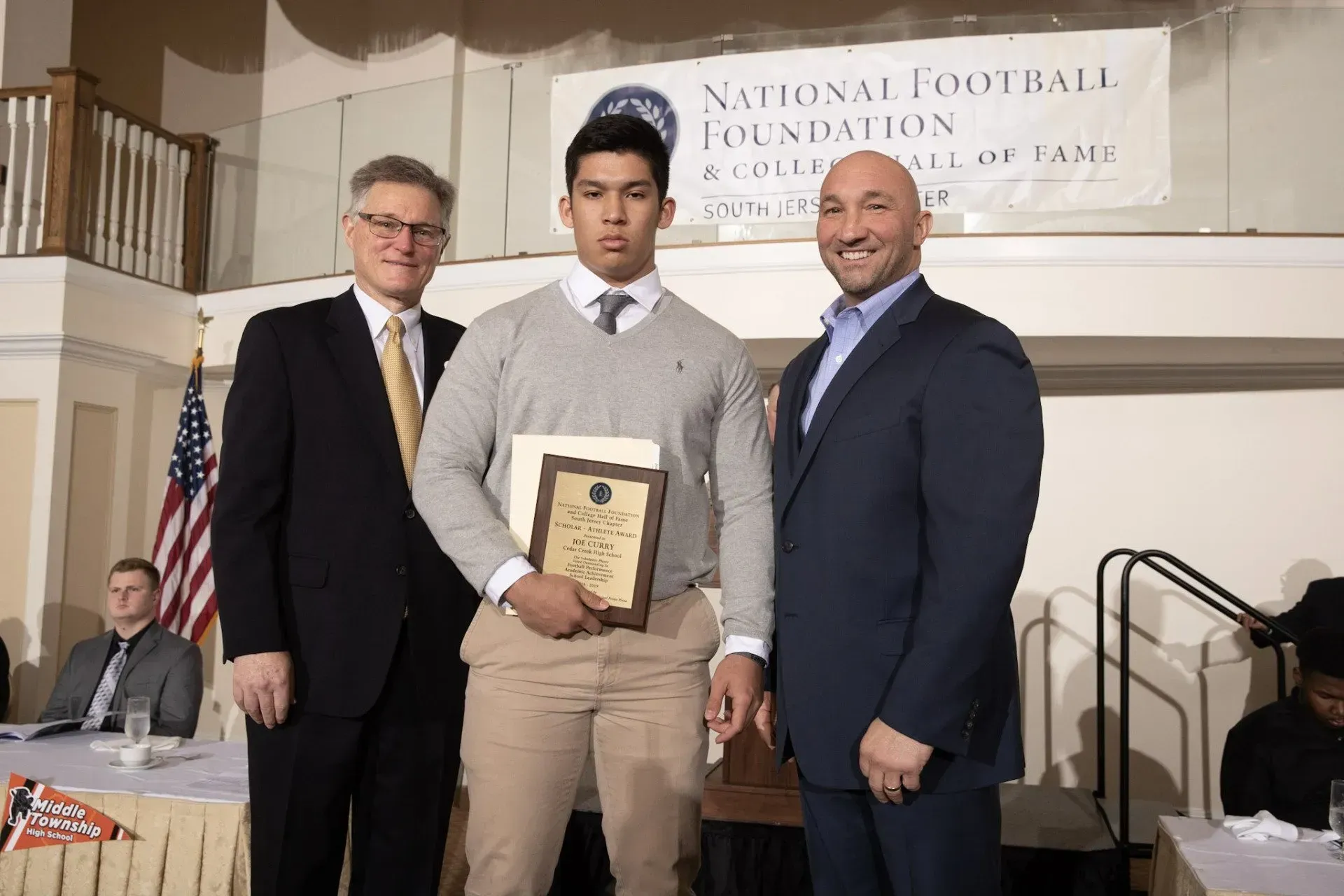 three men standing in front of a sign that says national football foundation