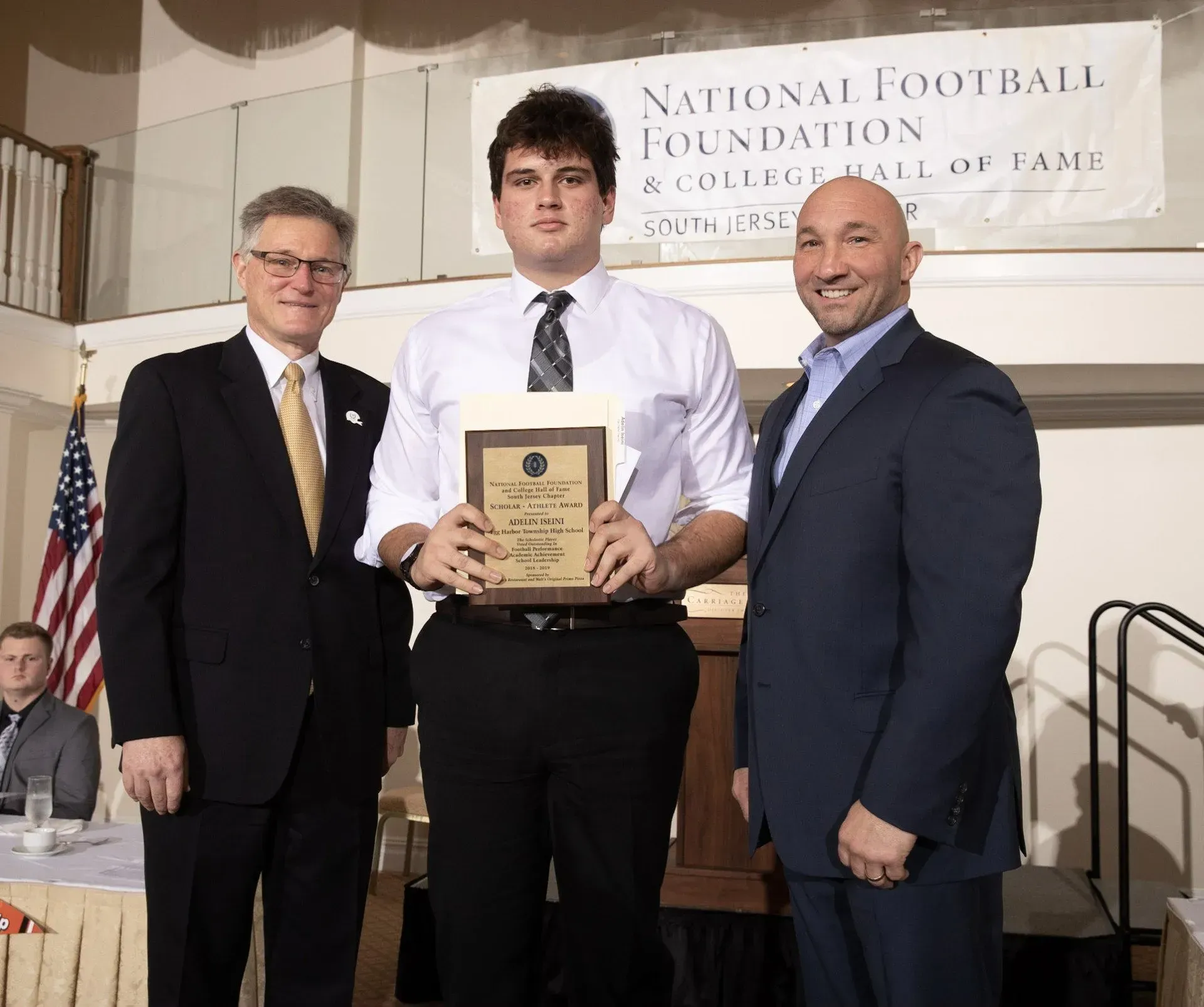 three men standing in front of a sign that says national football foundation