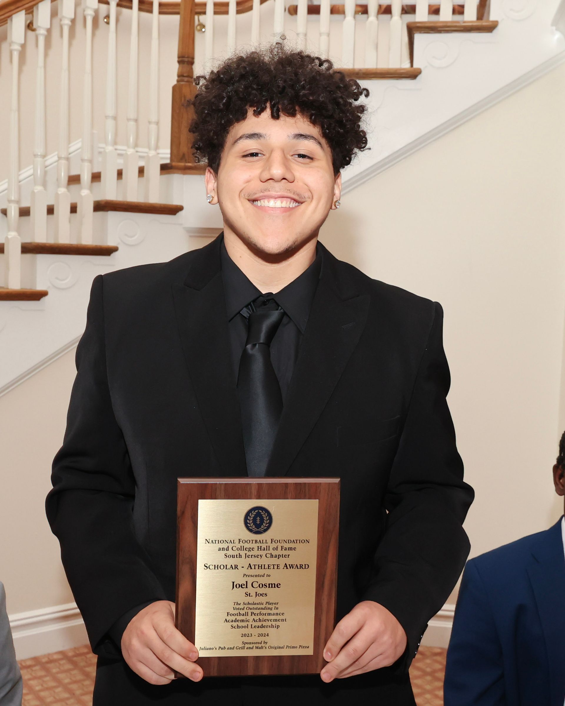 A man in a suit and tie is holding a plaque