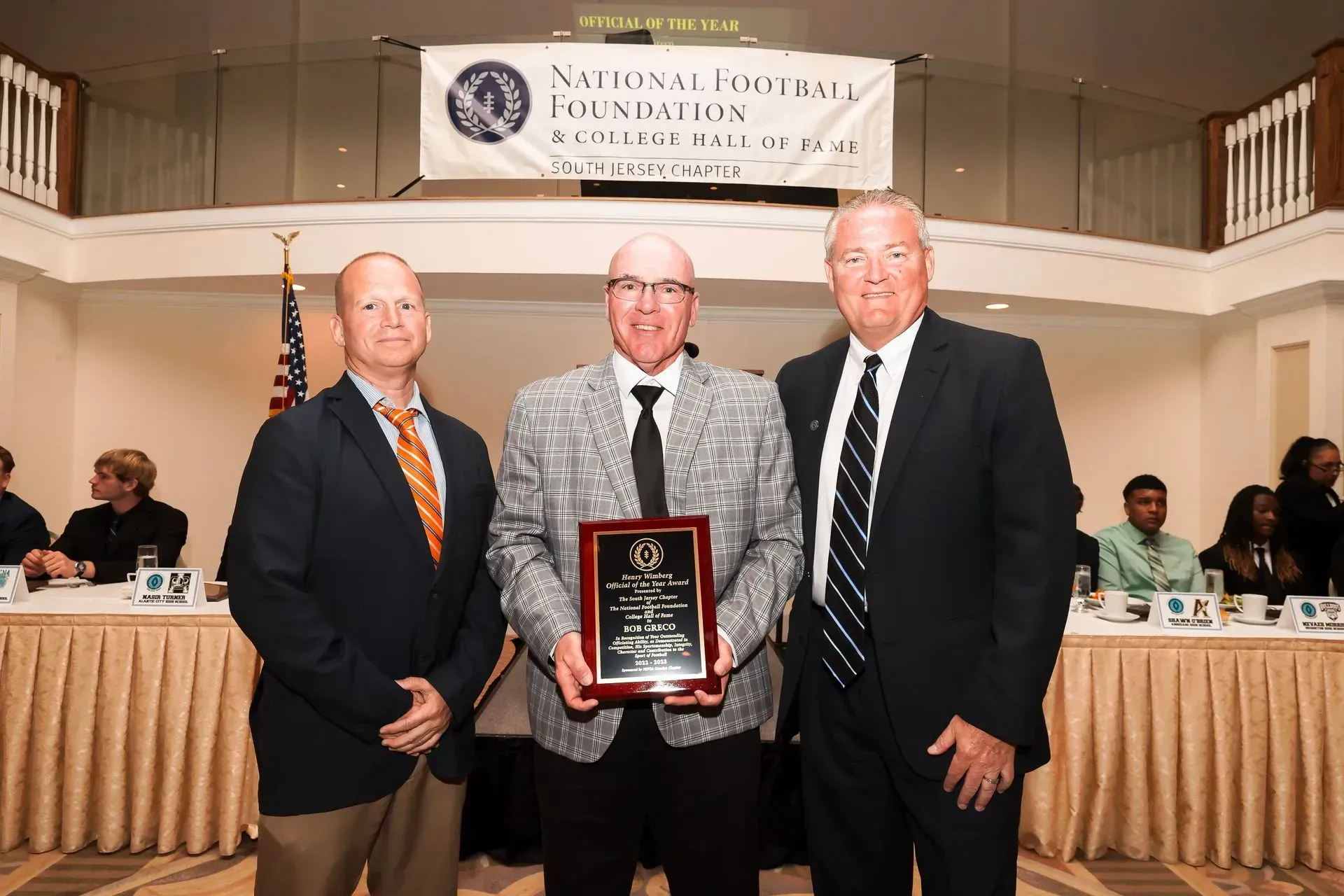 three men pose for a picture in front of a banner that says national association