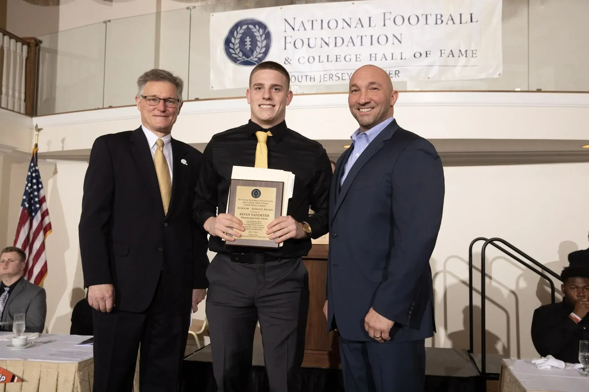 three men standing in front of a national football foundation banner