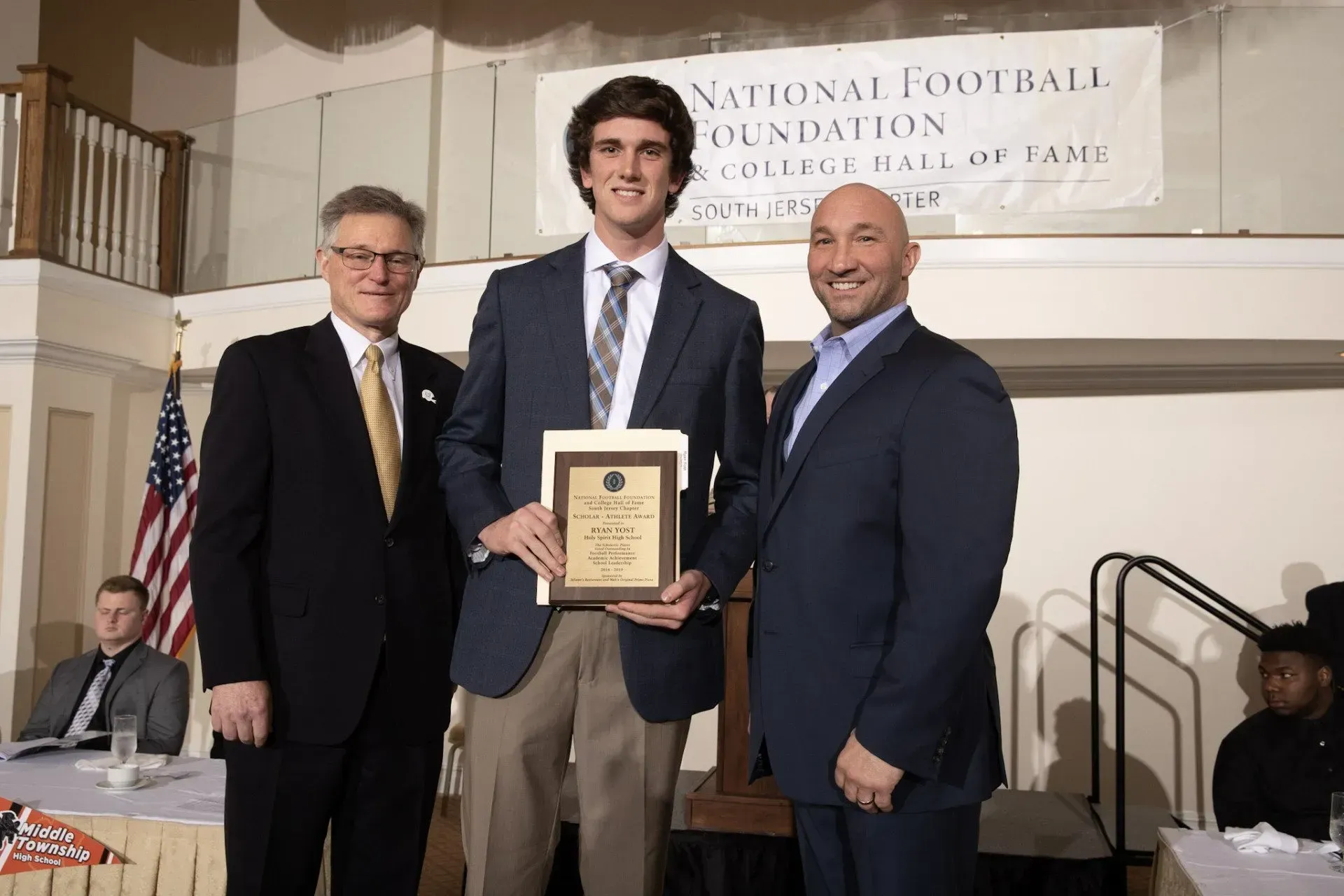 three men standing in front of a national football foundation banner