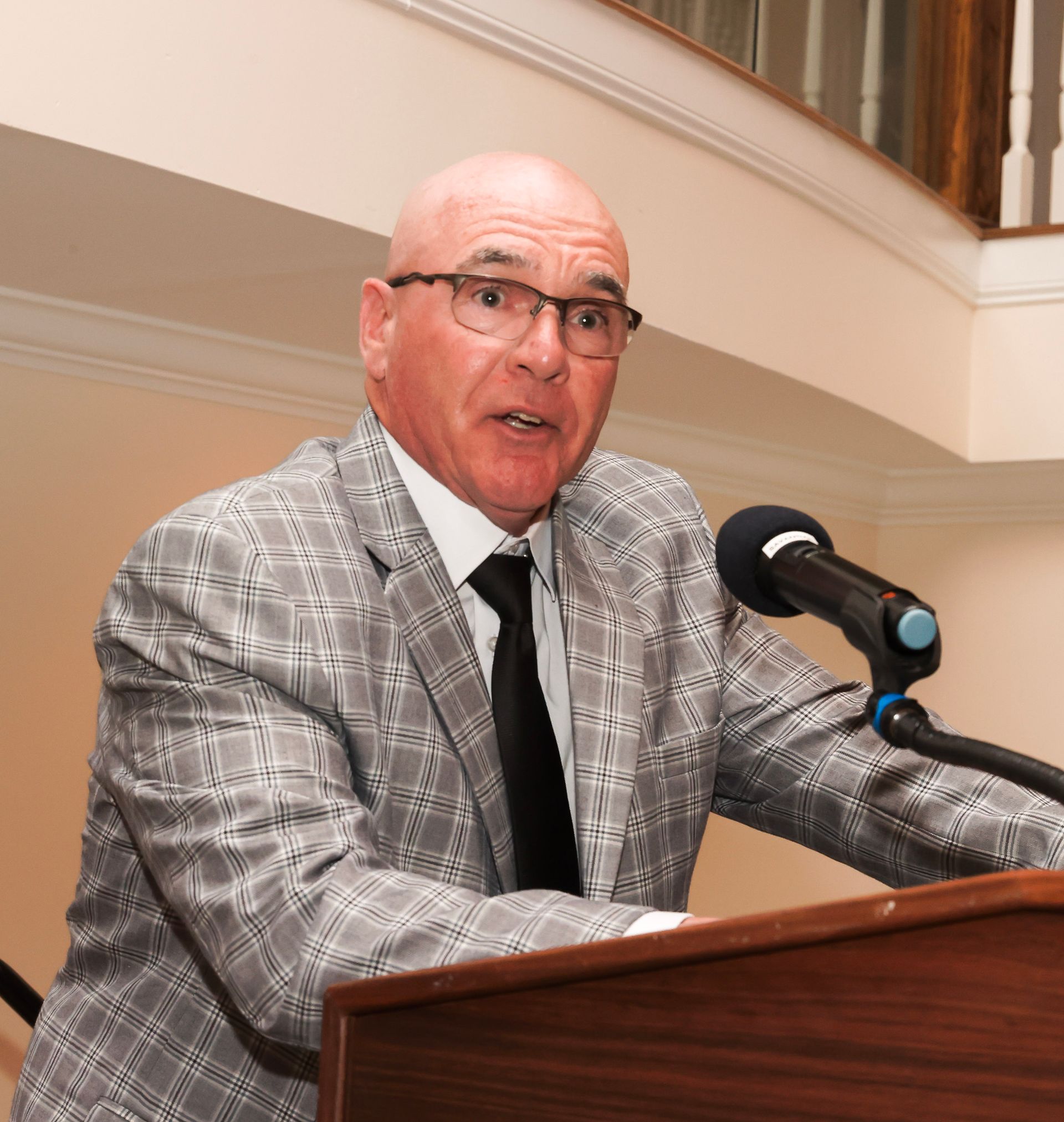 a man in a suit and tie is speaking into a microphone