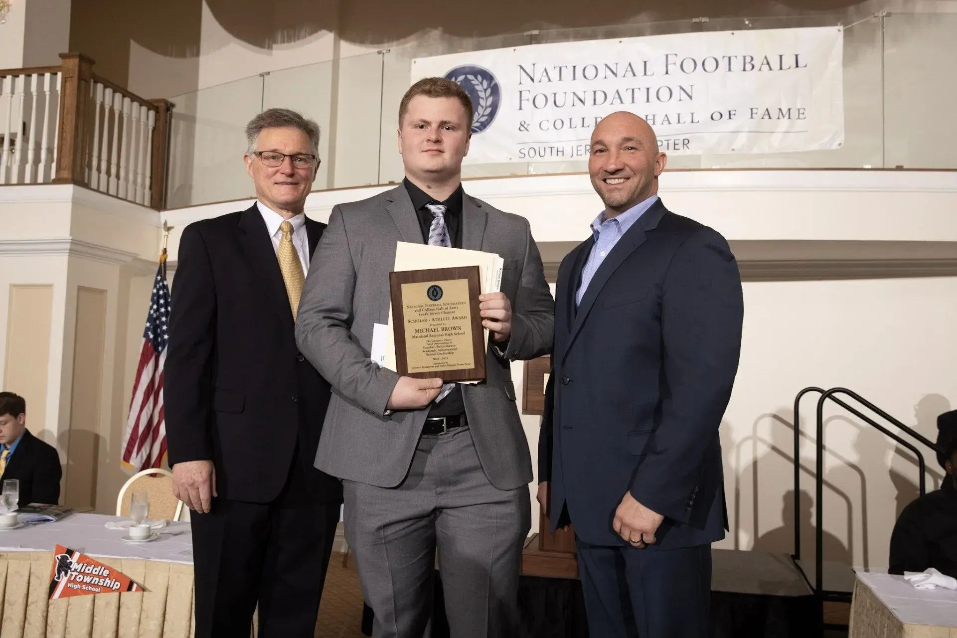 three men are standing in front of a sign that says national football foundation
