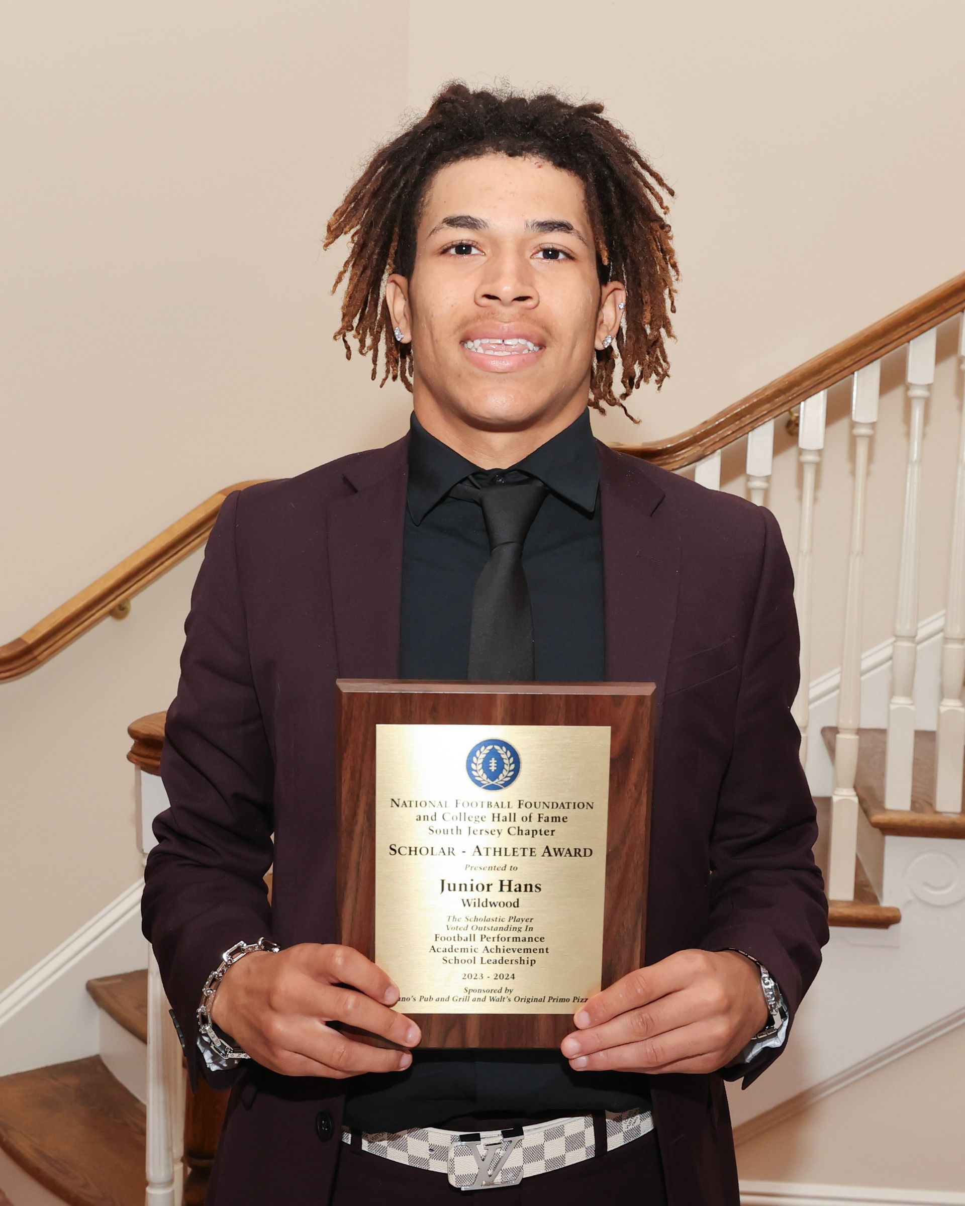 A young man in a suit and tie is holding a plaque