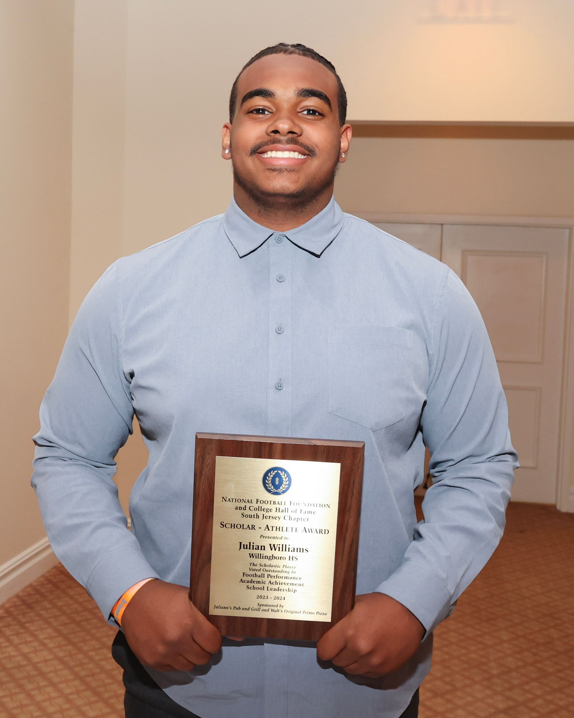 A man in a blue shirt is holding a plaque