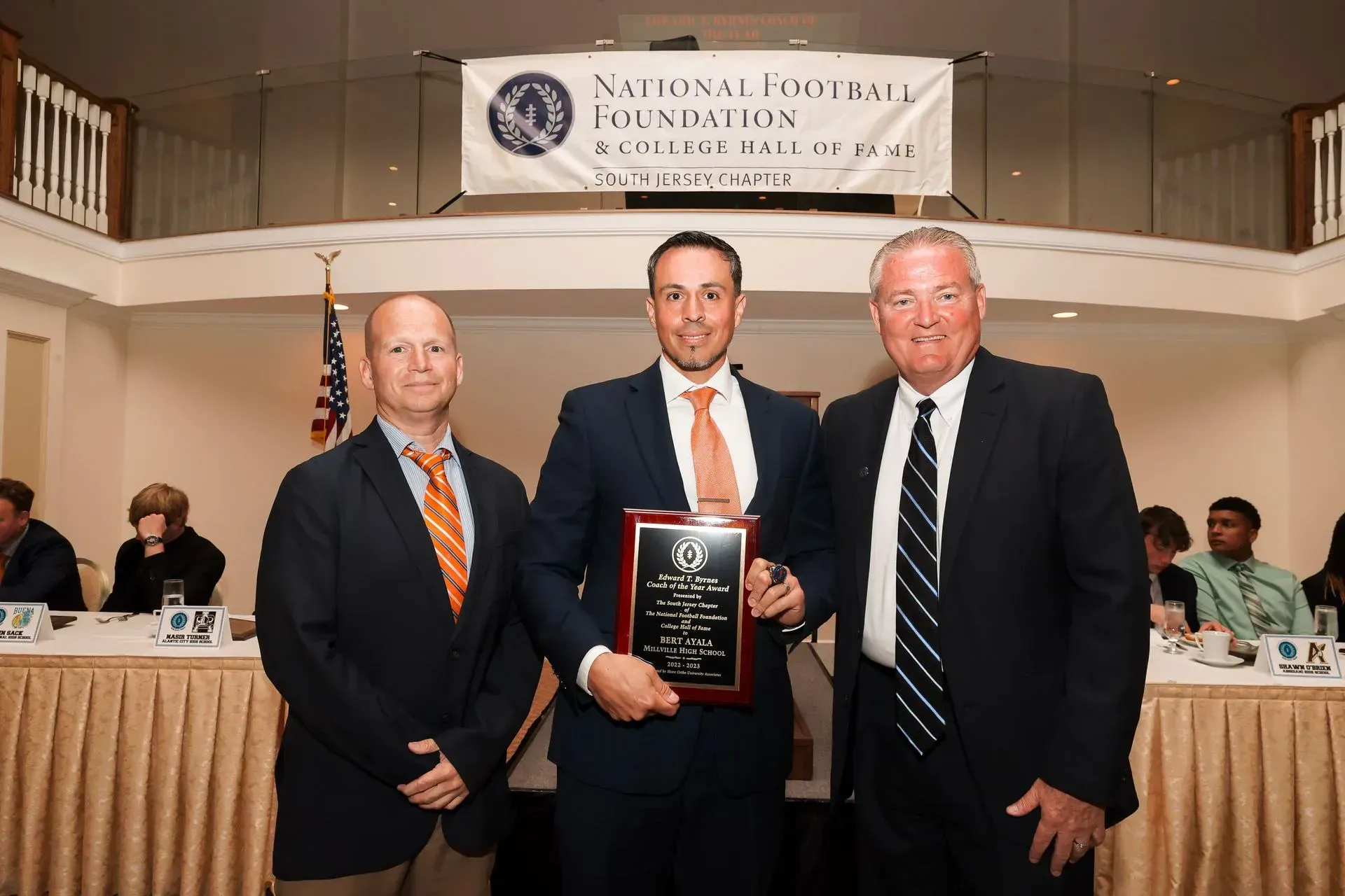 three men are posing for a picture in front of a national society banner