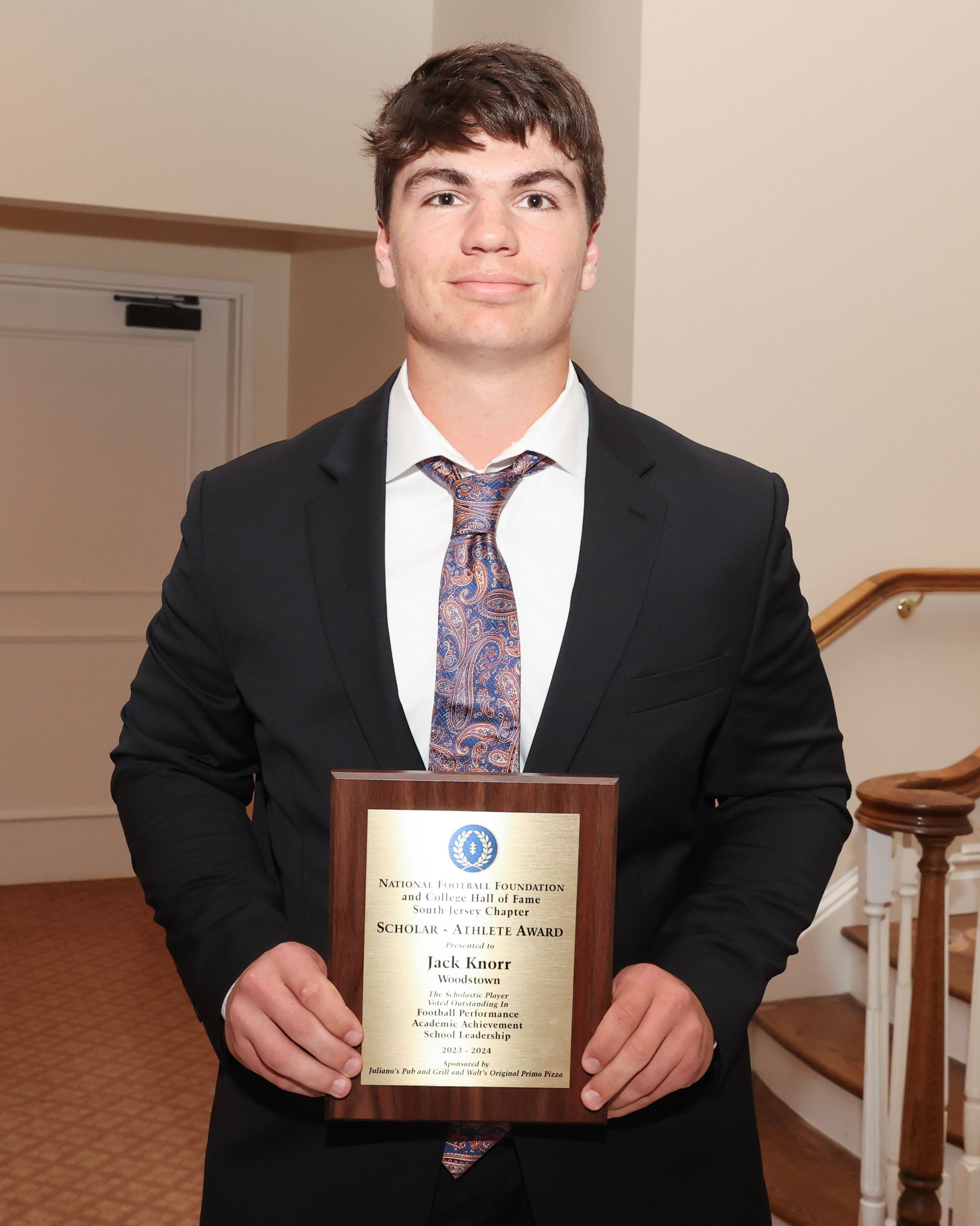 A man in a suit and tie is holding a plaque