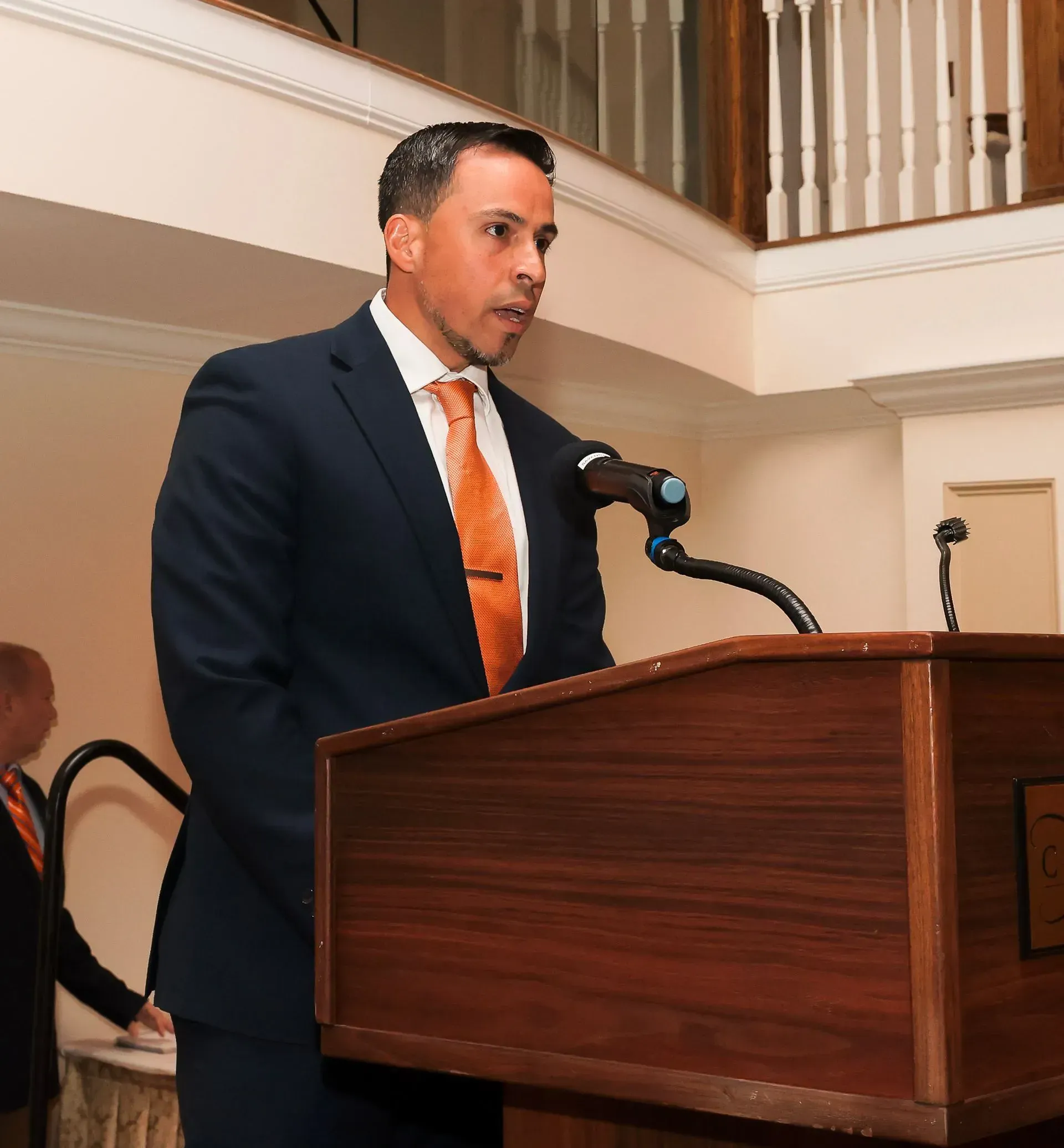 a man in a suit and tie is speaking into a microphone