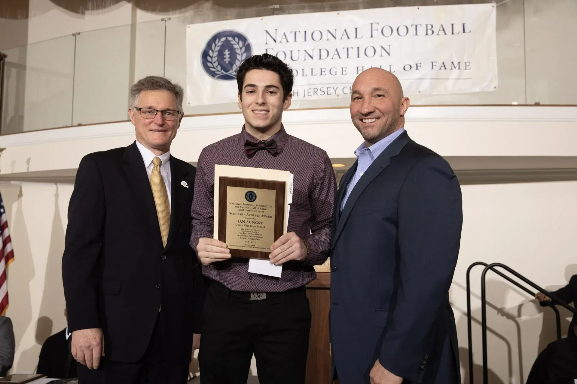 three men standing in front of a national football foundation banner