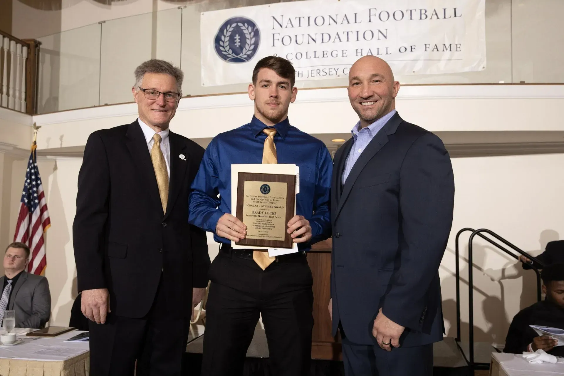 three men standing in front of a national football foundation banner