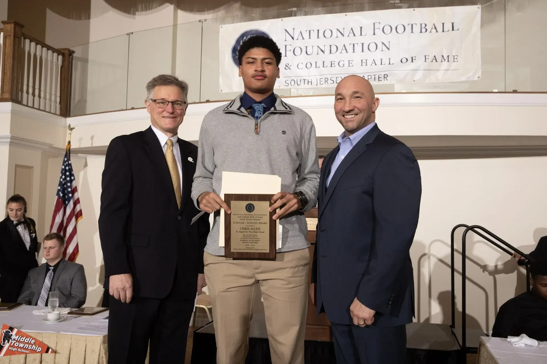 a man is holding a plaque in front of a national football foundation banner