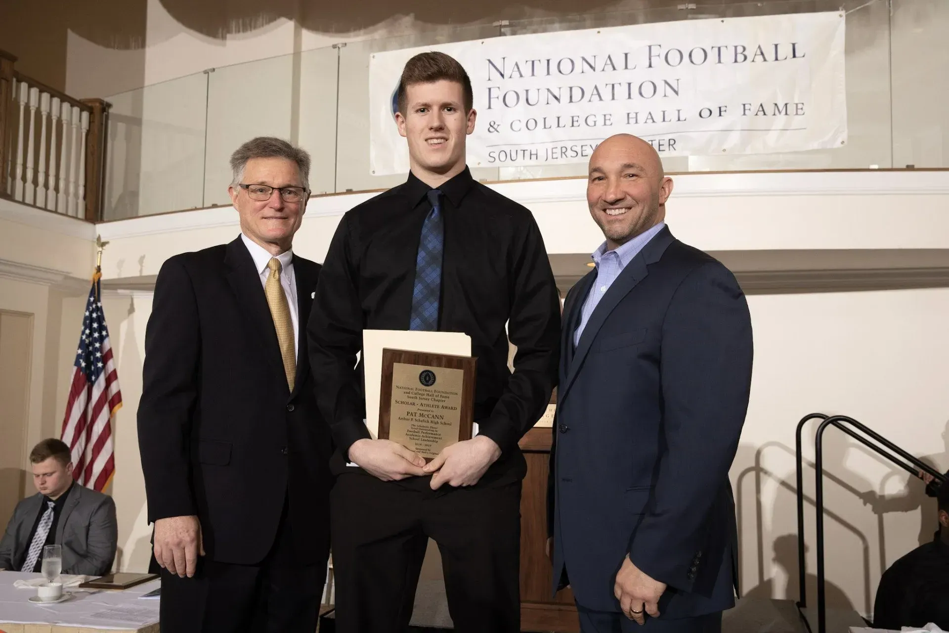 three men standing in front of a sign that says national football foundation